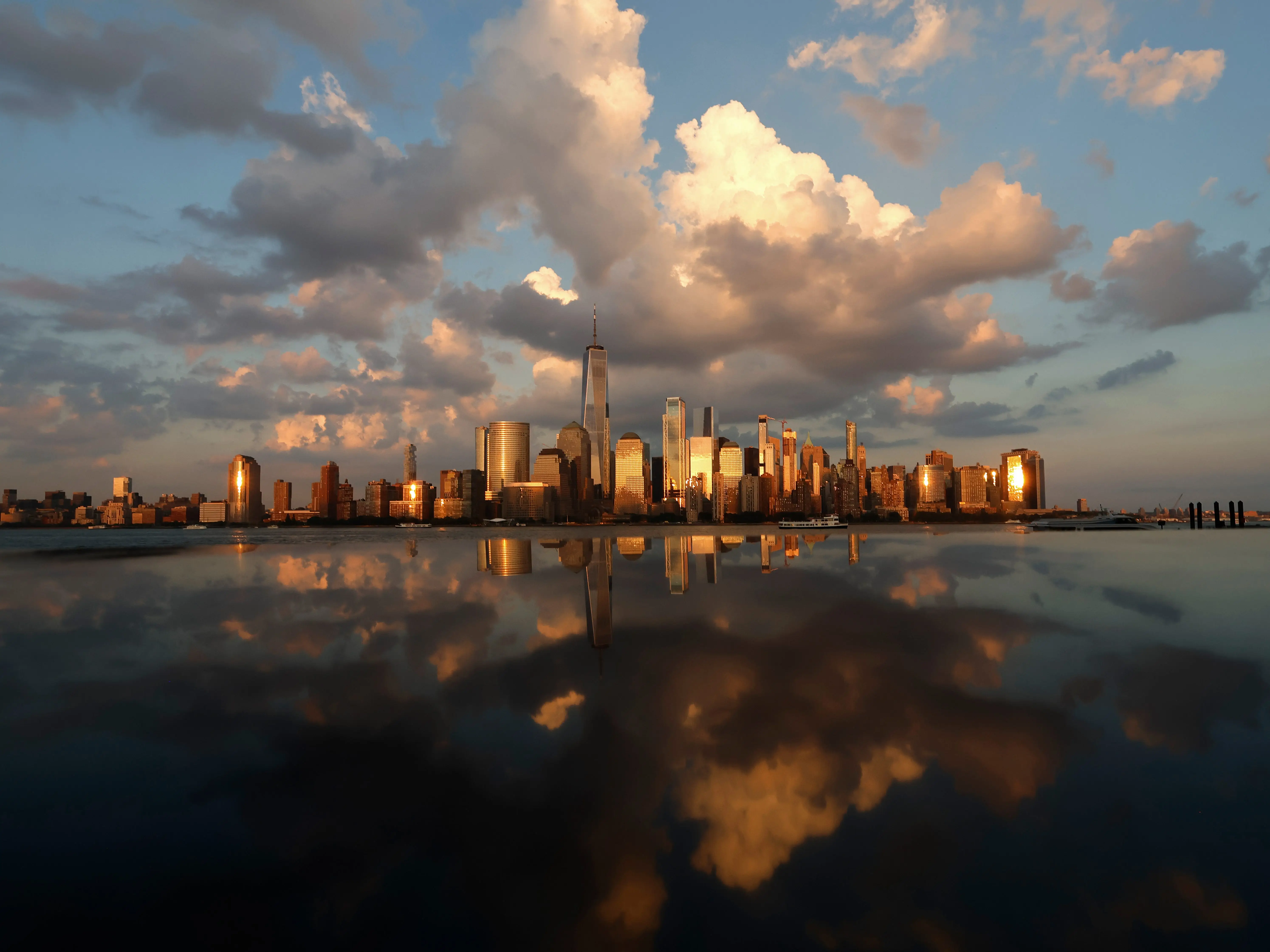 A photo of a major American city during sunset, with the sky reflected in the water at the foreground.