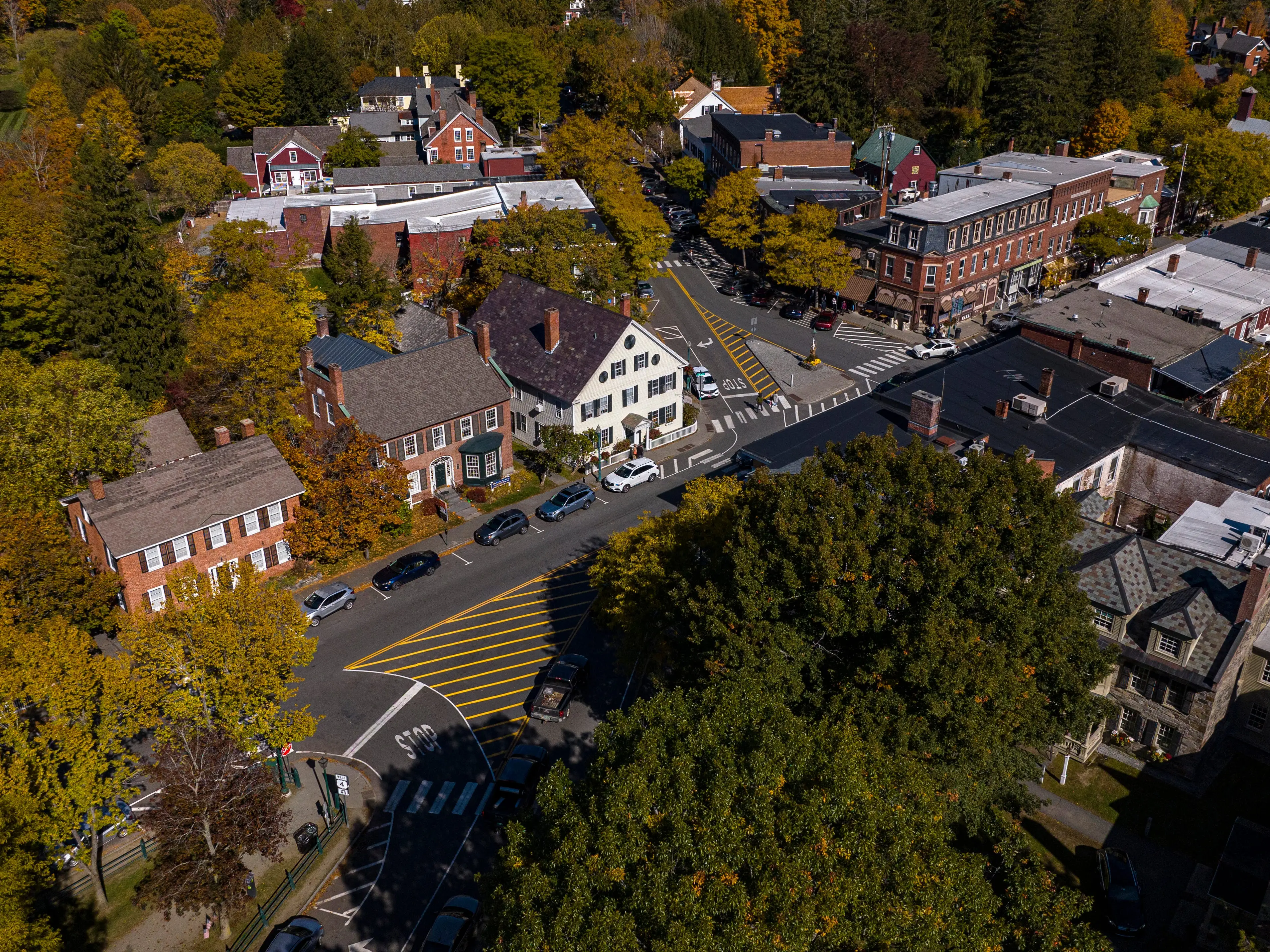 An aerial image of a small downtown area surrounded by trees adorned with fall colors.