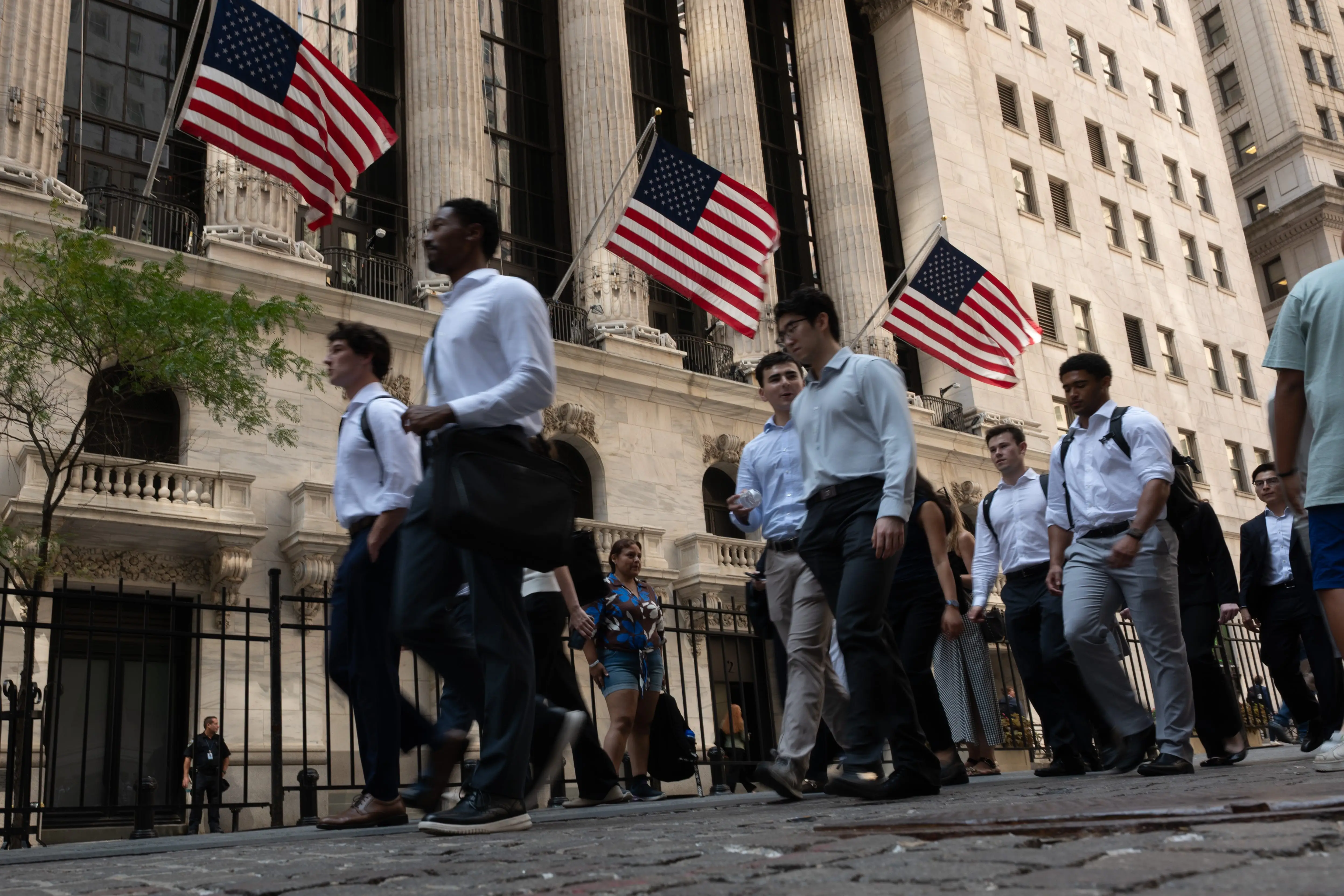 Young professionals walk by the New York Stock Exchange