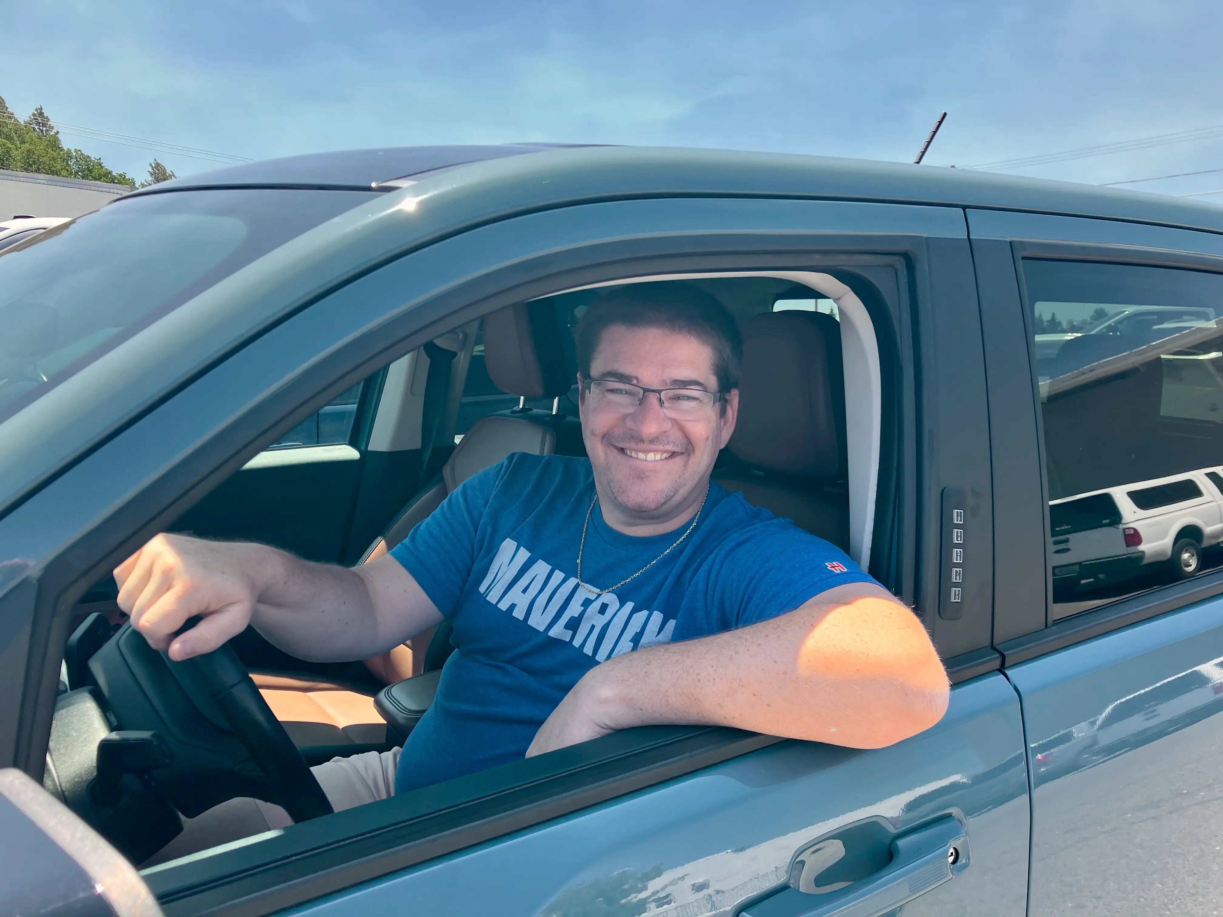 Chris Astrella smiles at the camera while sitting in the driver's seat of a new-to-him car.