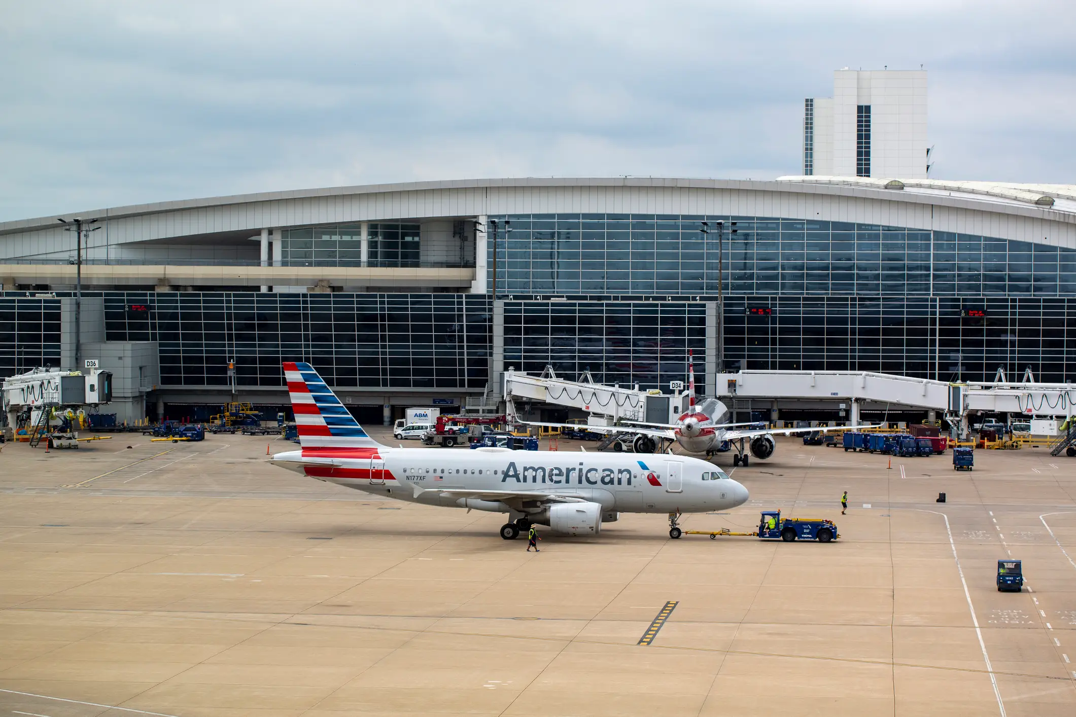 An American Airlines jet is towed on an airport apron in front of a glass terminal building at Dallas-Fort Worth.