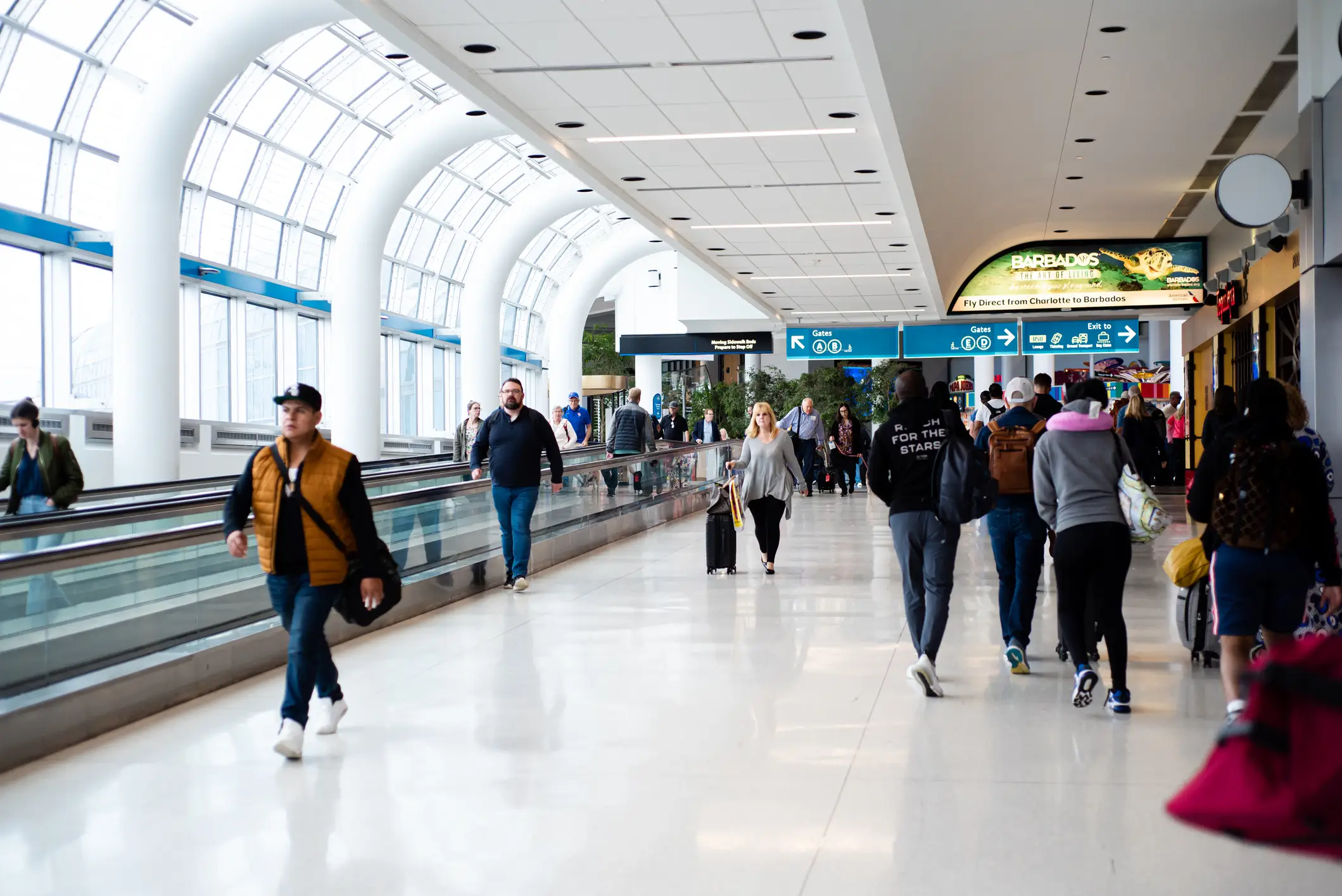 Slow-moving conveyor or autowalk with a group of travelers inside Charlotte Douglas International Airport.