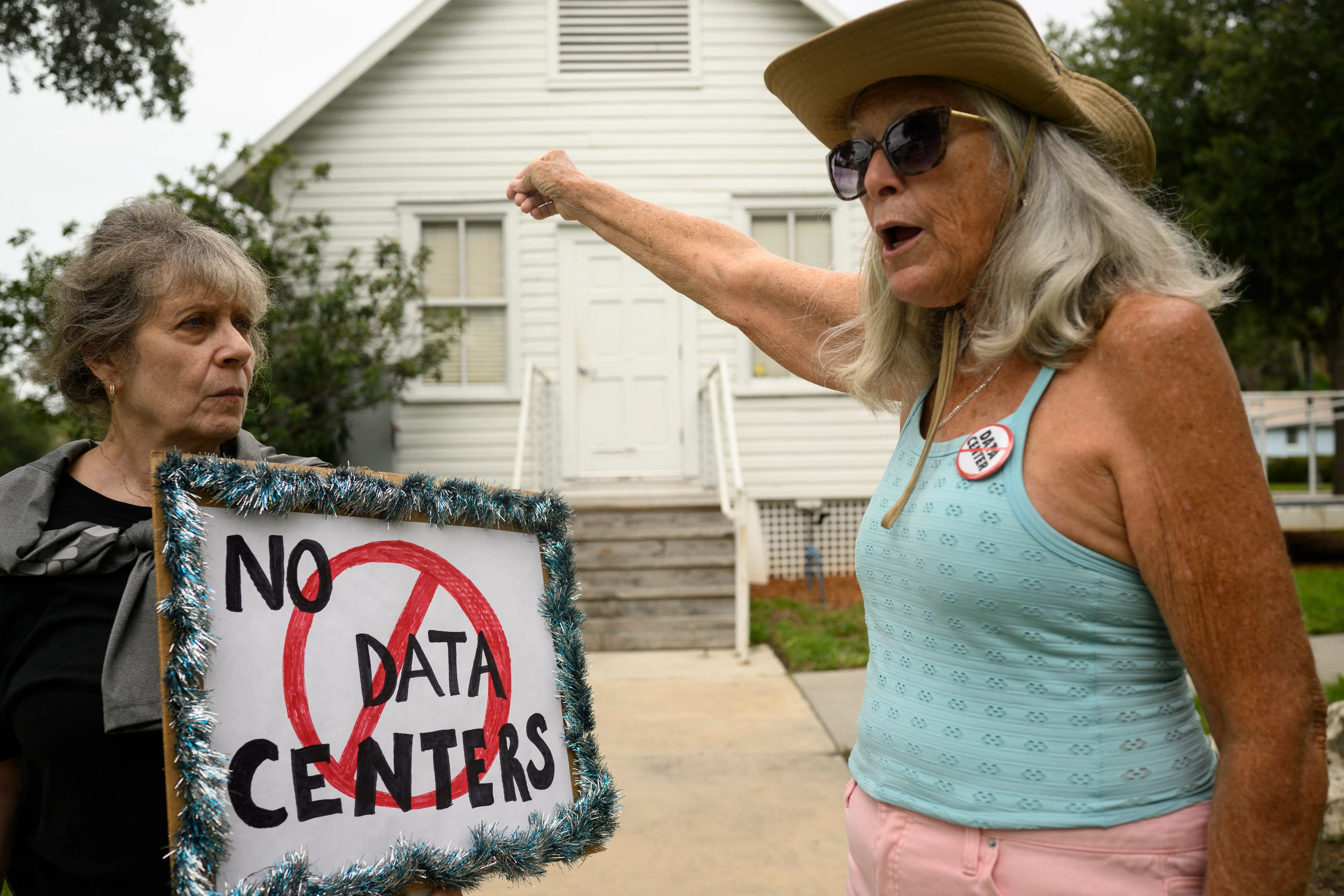 People hold signs during a nationwide protest against AI data center expansion outside Peace Hall in New Port Richey, Florida on July 18, 2026.