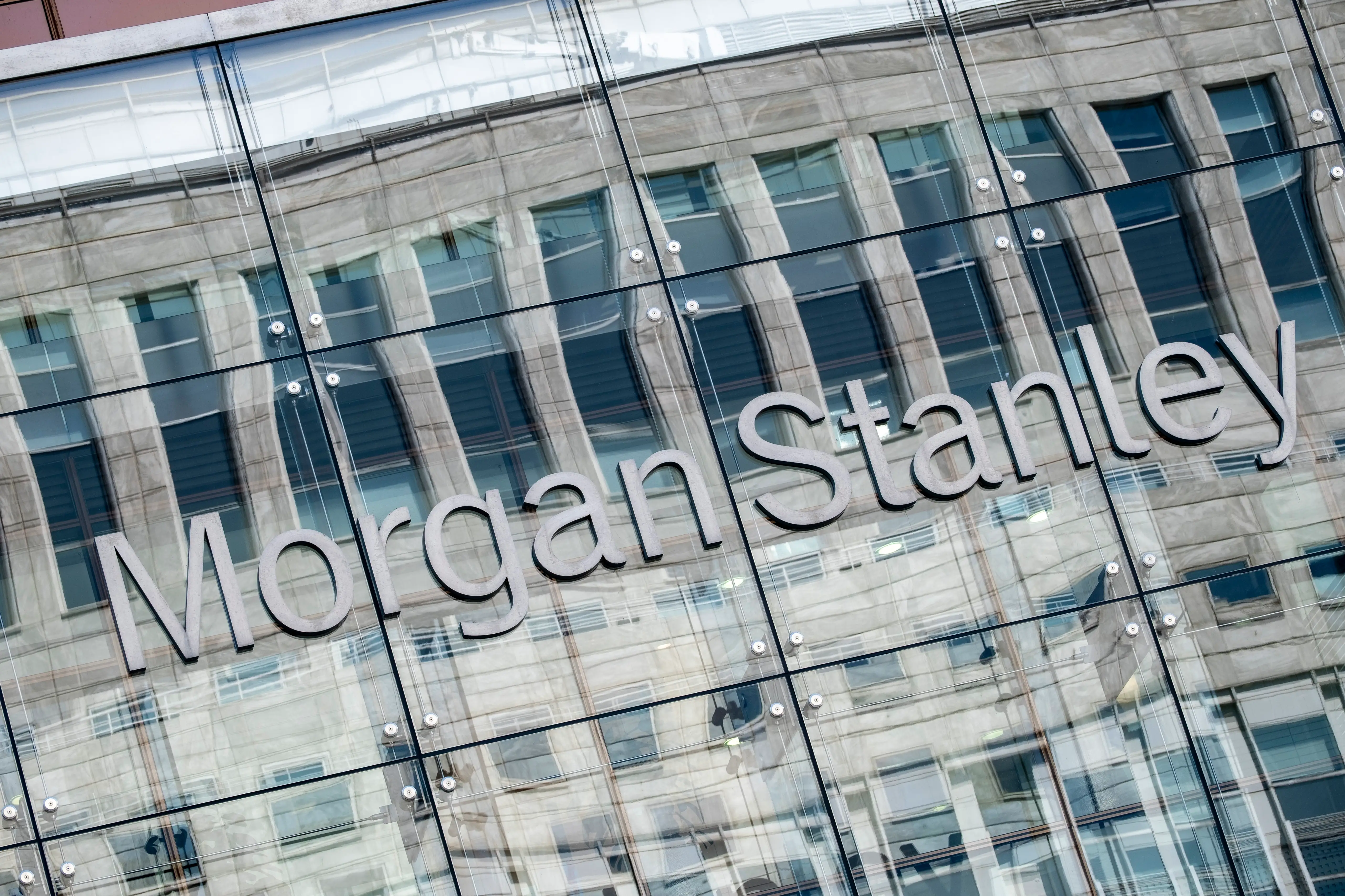 Morgan Stanley signage appears on a glass building facade reflecting surrounding office windows.
