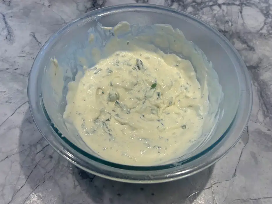 A bowl of buttermilk herb mayo, made with a mix of mayo, buttermilk, vinegar, scallions, parsley, chives, and thyme.