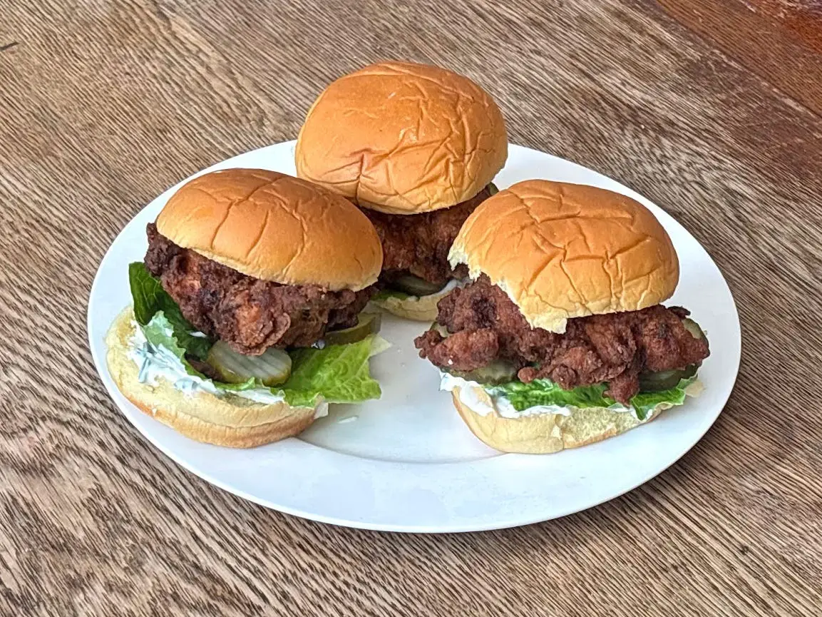 Three fried-chicken sandwiches on a white plate.