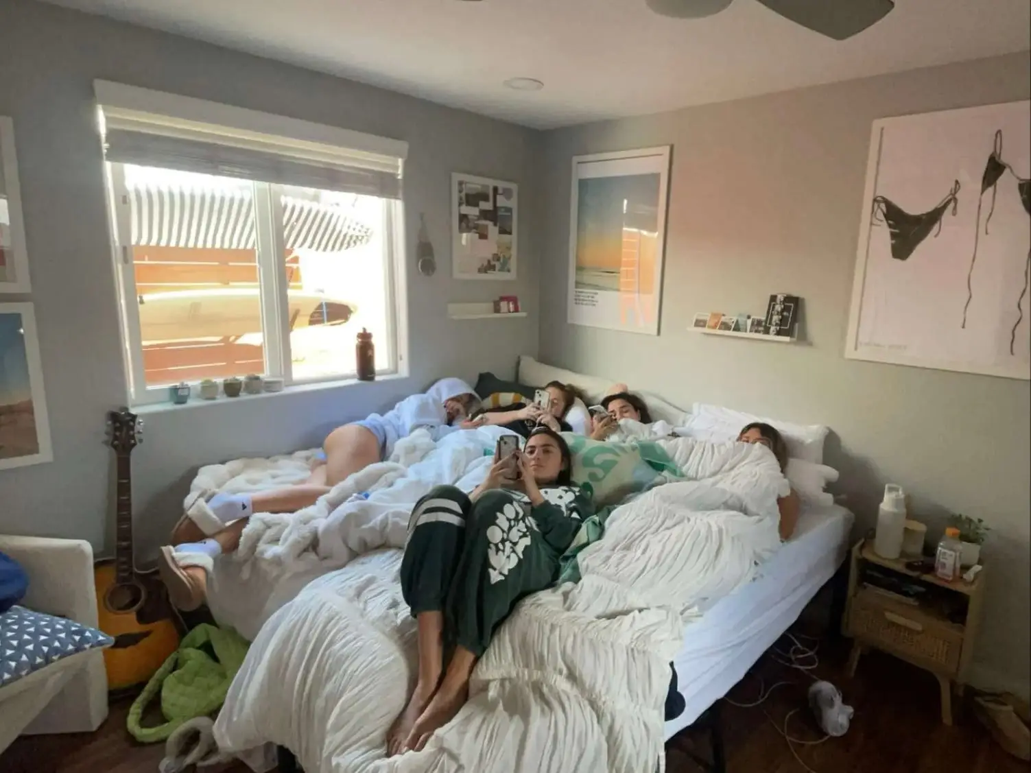 The writer and her roommates pile onto a large bed made by pushing two twin beds together in their California home.