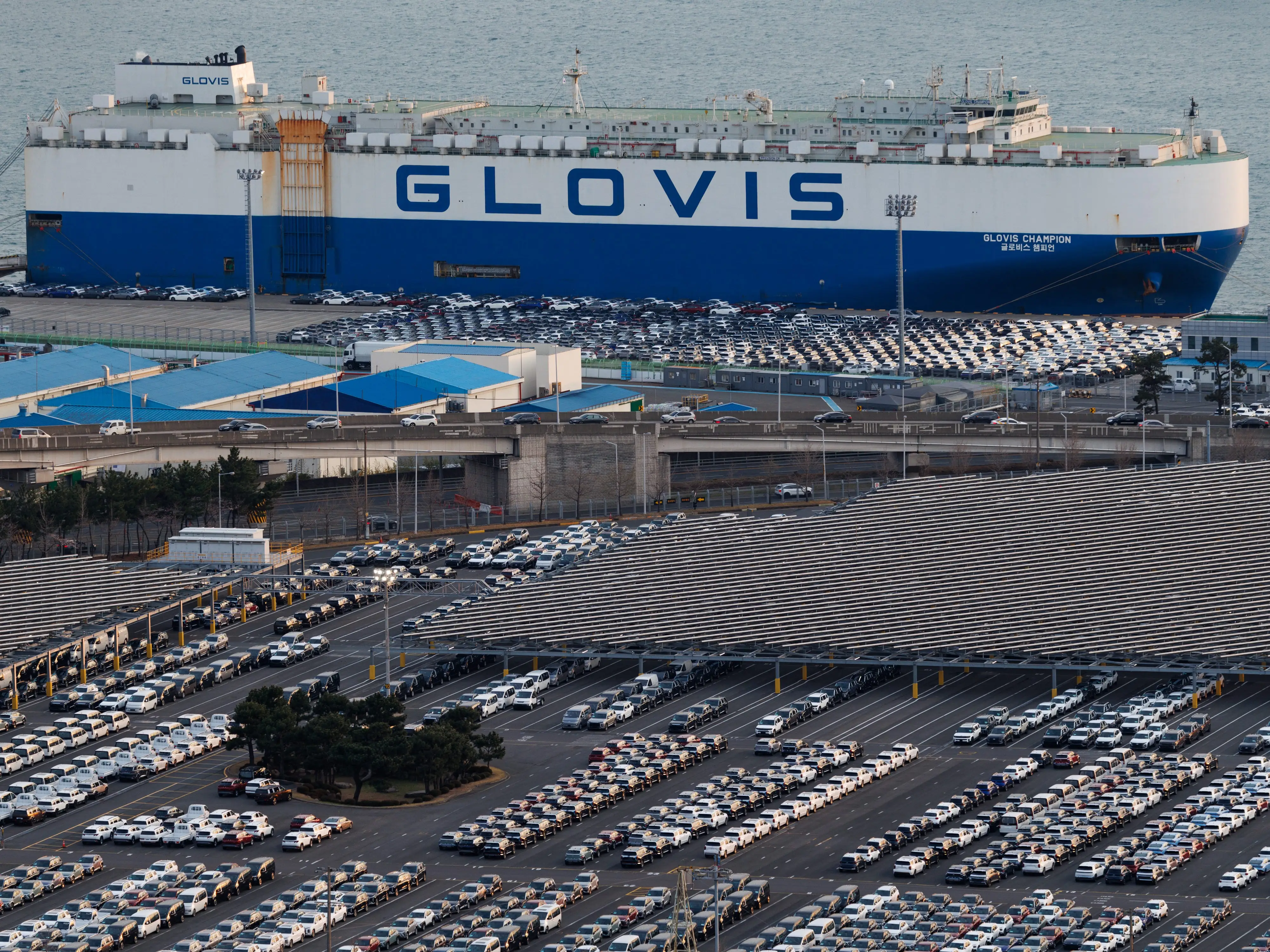 Hyundai cars parked by Hyundai cargo ship.