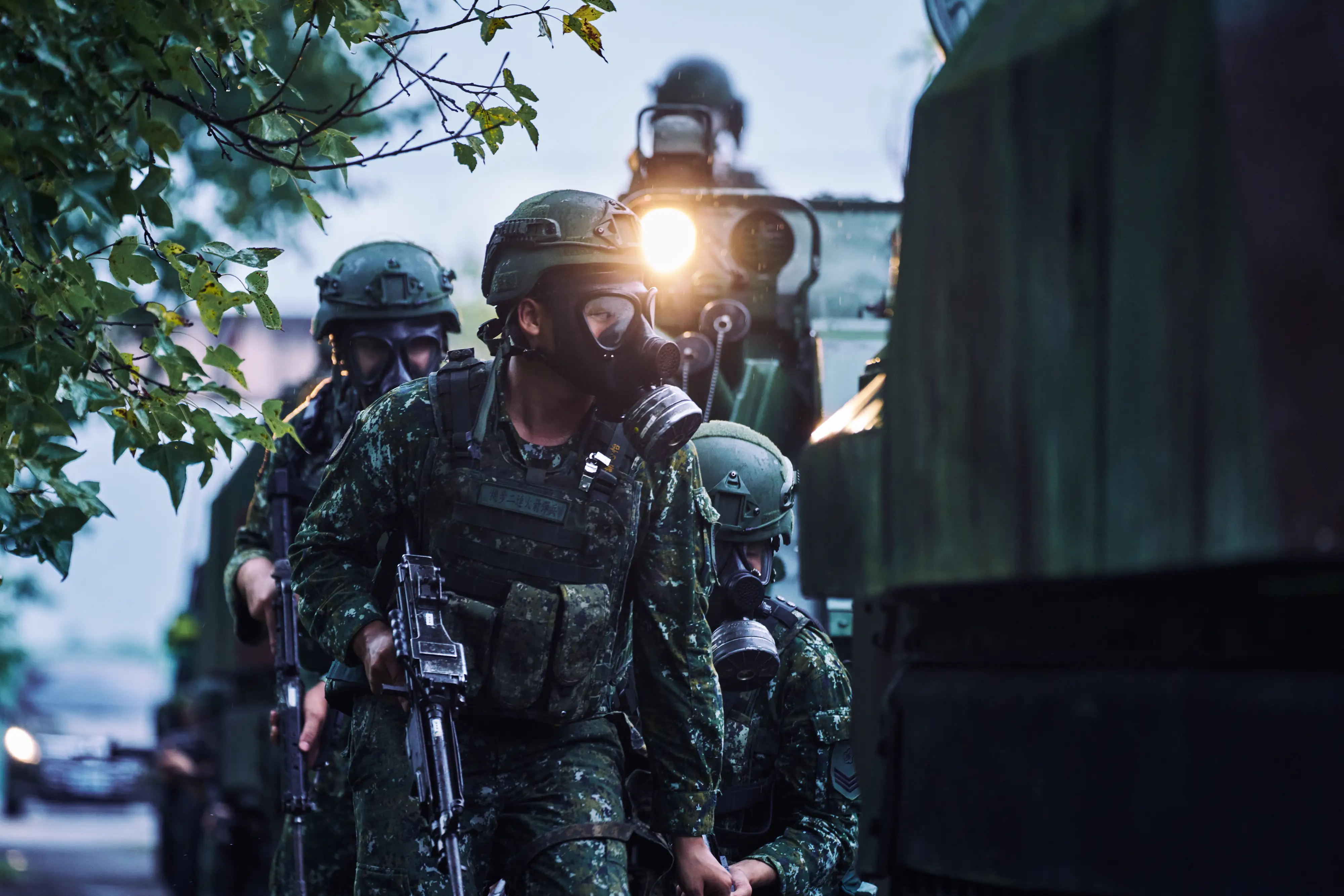 Taiwanese infantry with gas masks reposition next to armored vehicles.