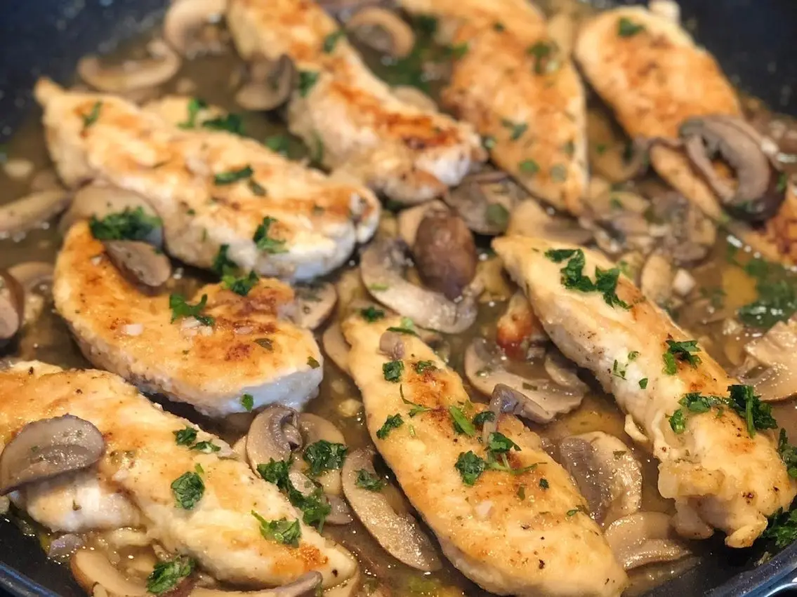 Chicken cooked with herbs and mushrooms in a pan.