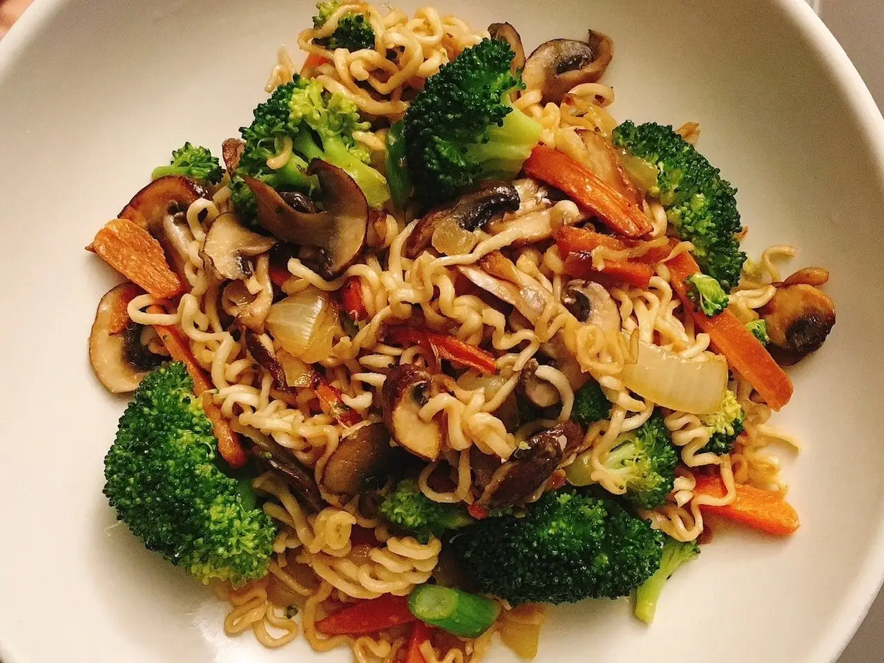 Noodles stir-fried with broccoli, mushrooms, carrots, and onions in a bowl.