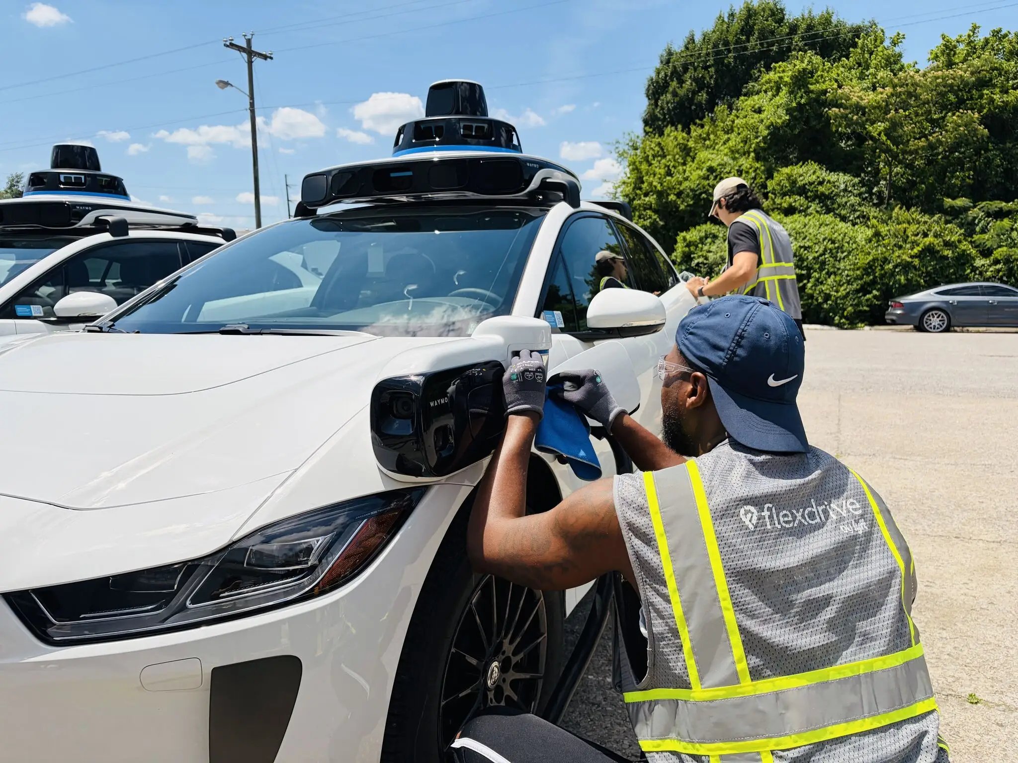 Two men working on a Waymo car.