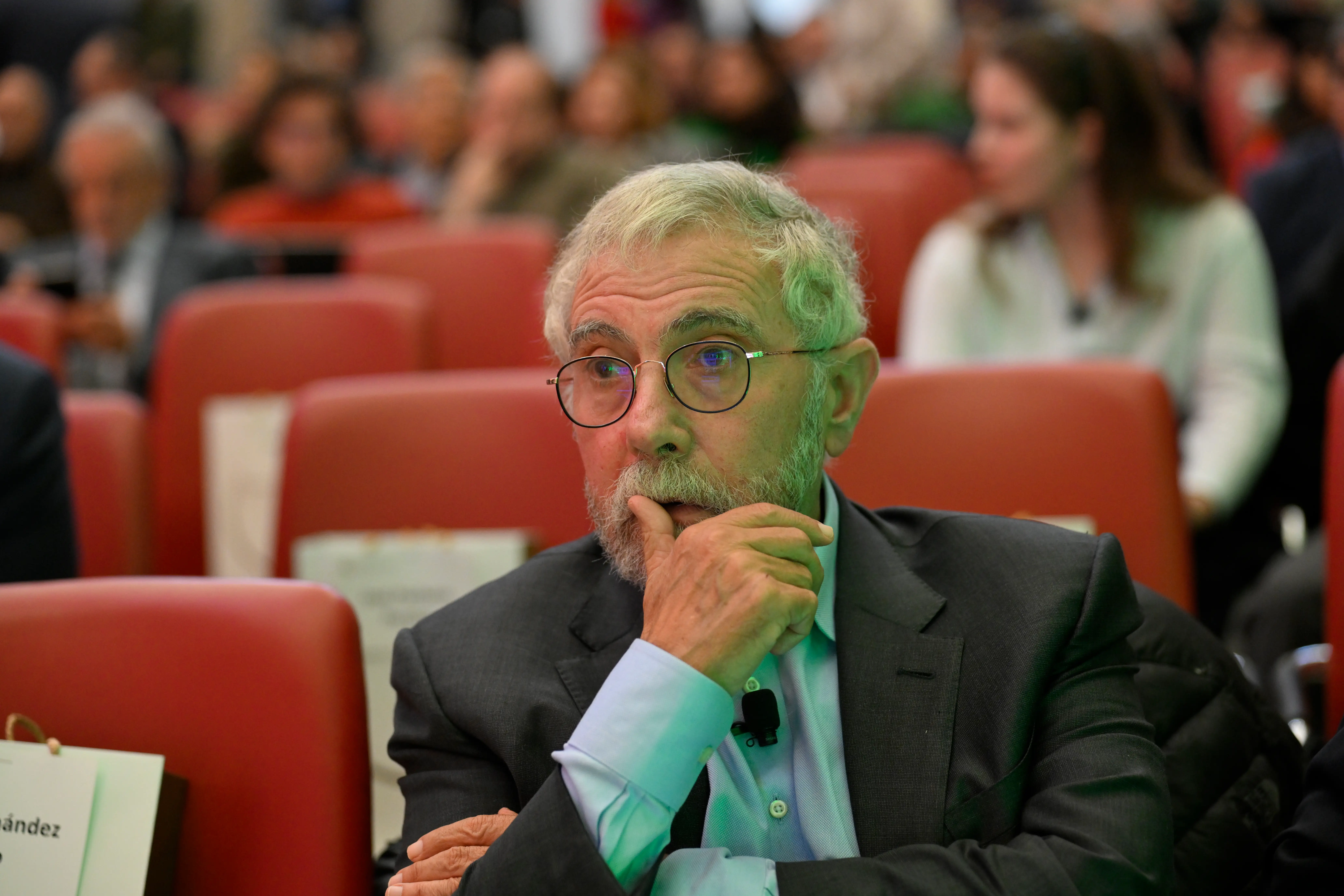 Economist Paul Krugman crosses his arms while sitting in a red chair.