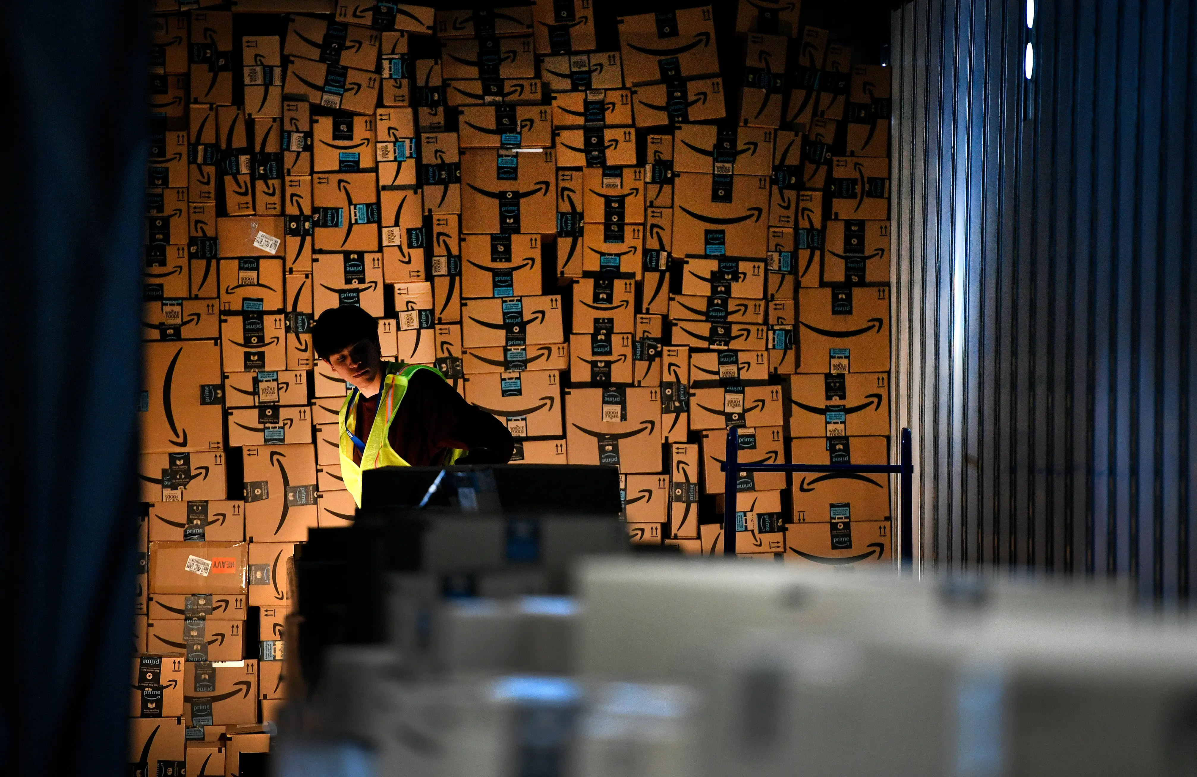 An Amazon worker loads boxes into a delivery vehicle