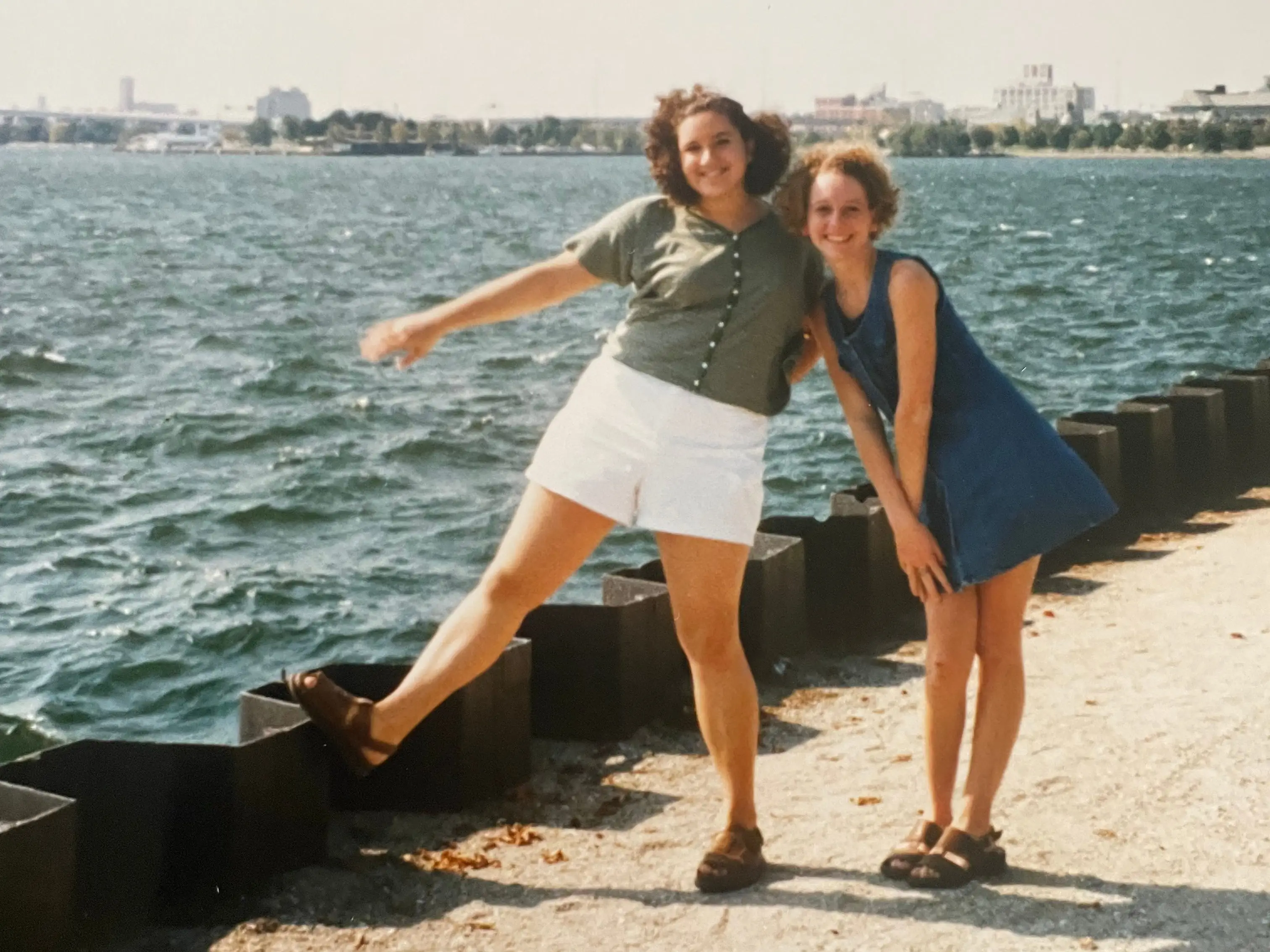 Two teen girls posing together near water