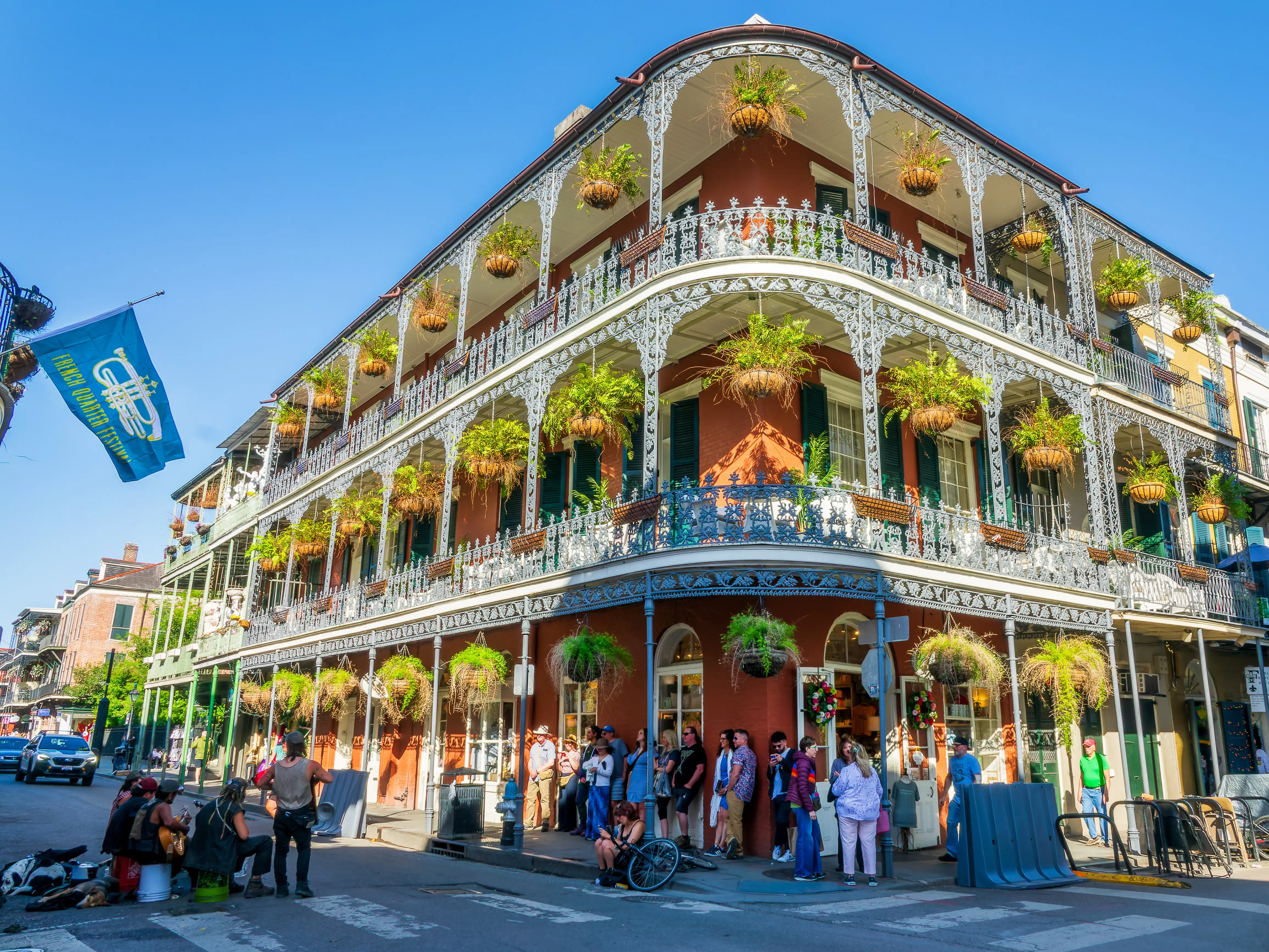 Music band, French Quarter Festival flag and historical LaBranche building with balconies and intricate ironwork columns in New Orleans, Louisiana