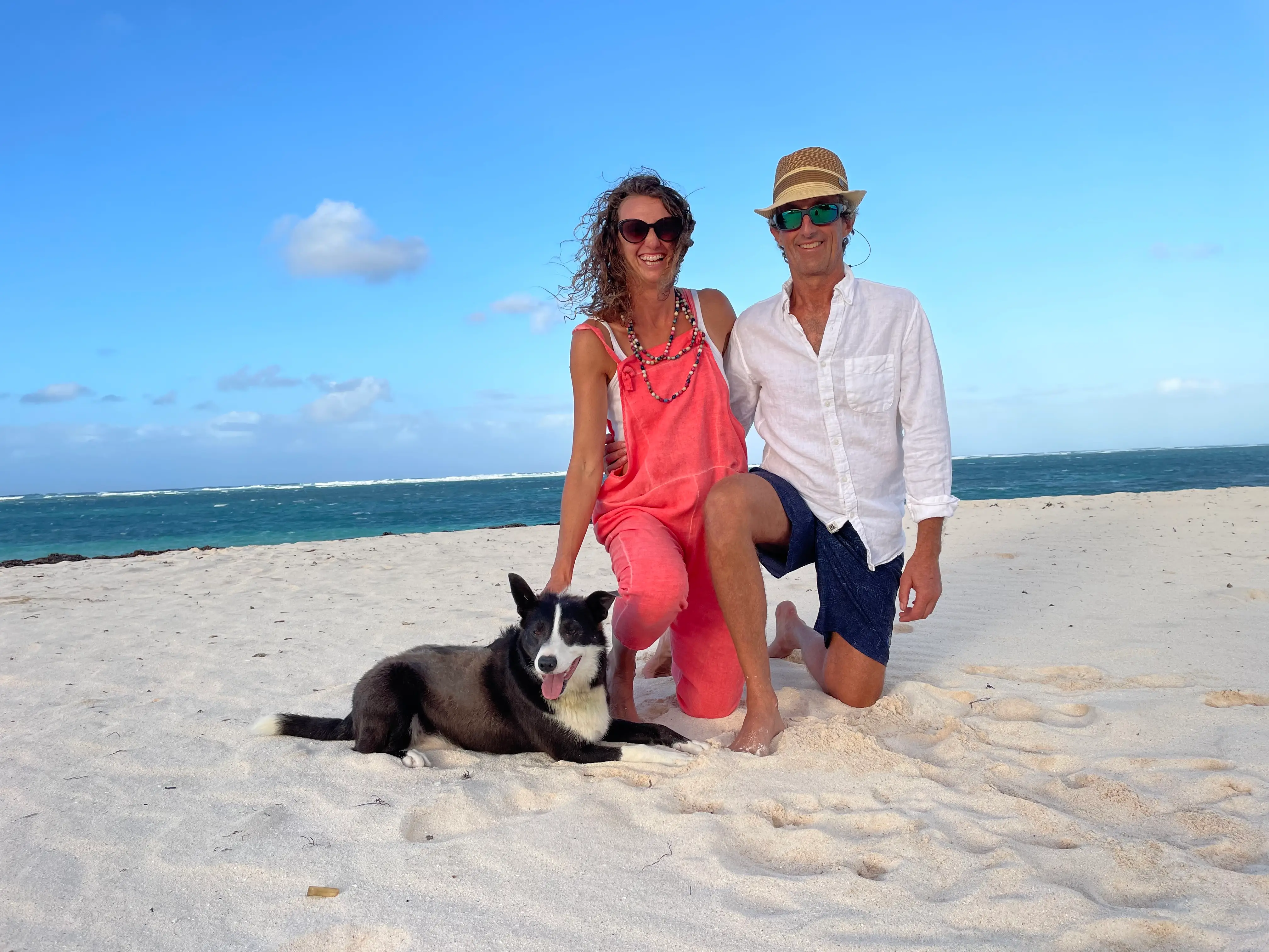 The author poses with her husband and a dog on a beach.