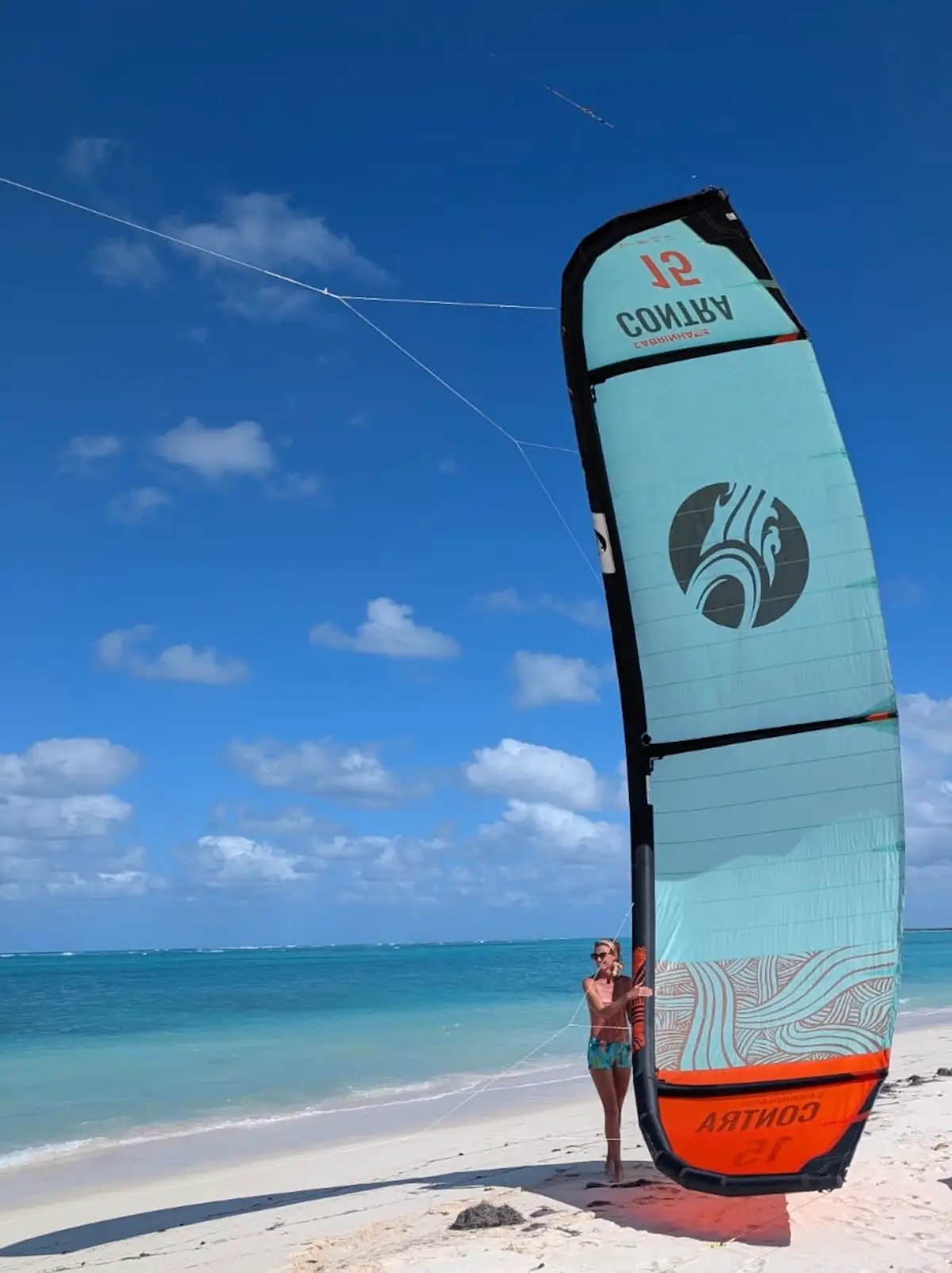 The author poses with a sail on a beach.