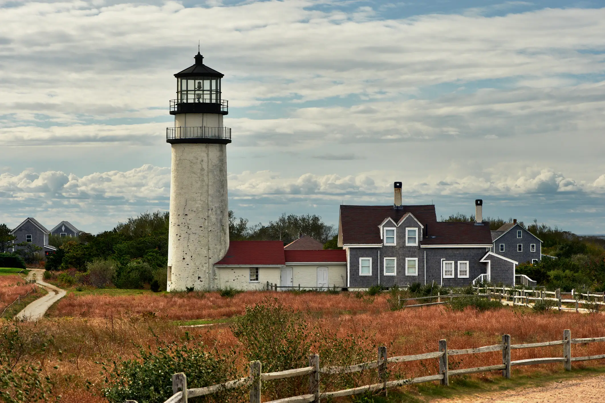 Highland Lighthouse behind wooden fencing under a cloudy sky.