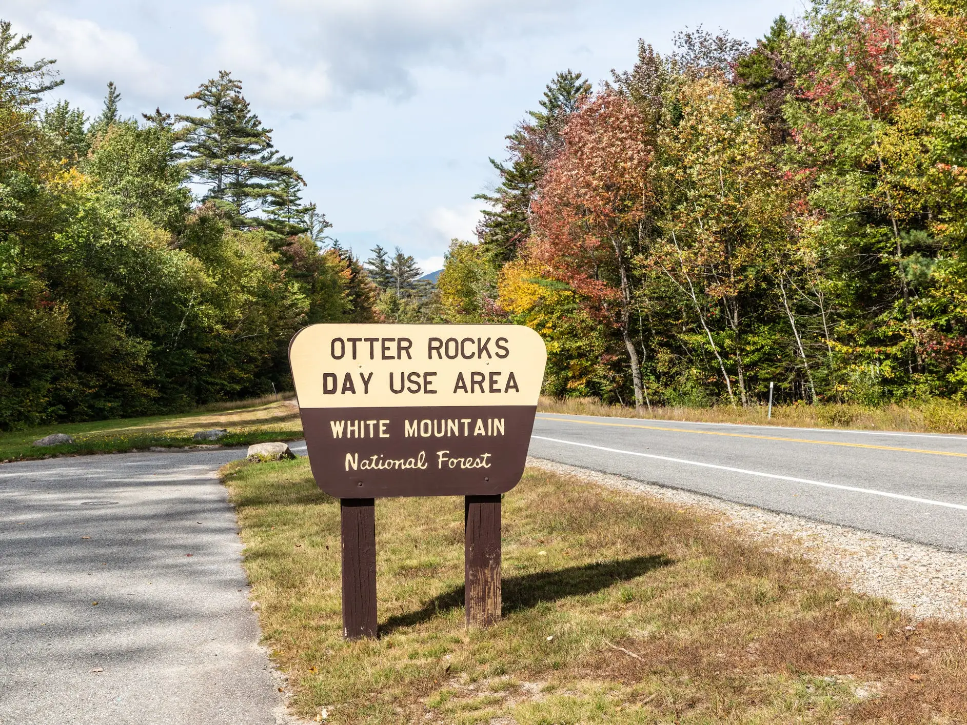 Otter Rocks Day Use Area sign stands beside a forest road in White Mountain National Forest.