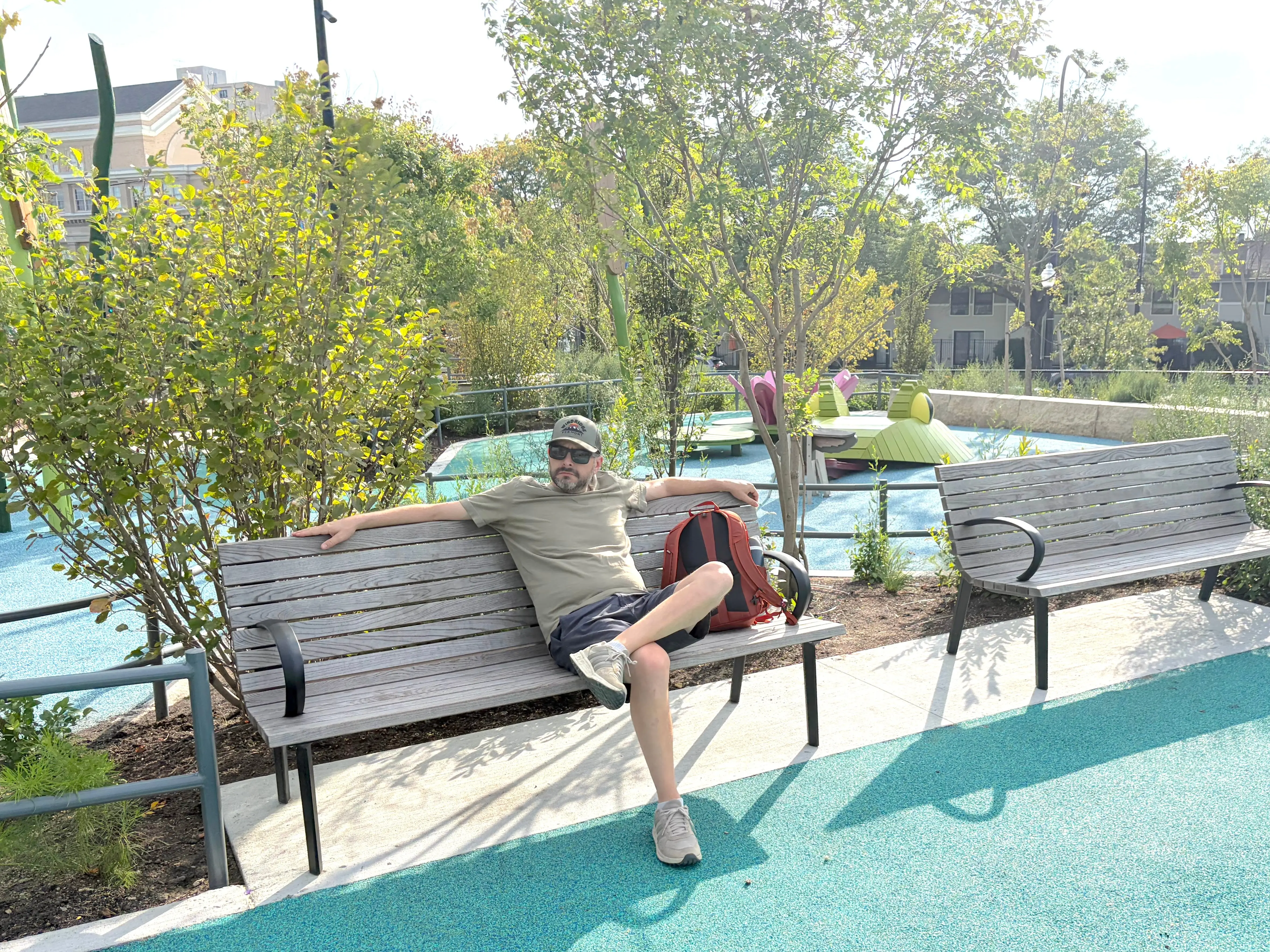 The author's husband sits on a bench at a playground at the Obama Presidential Center in Chicago's Jackson Park.