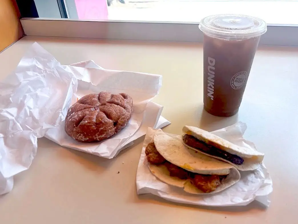 A coffee roll, two Wake-up wraps, and an iced coffee on a table.
