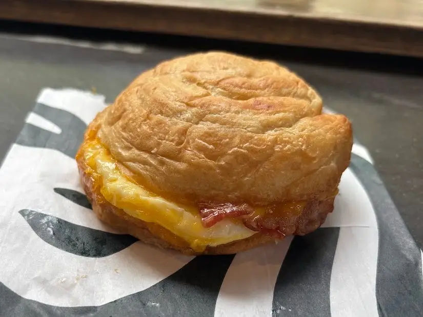 A bacon, egg, and cheese sandwich on a Starbucks bag.
