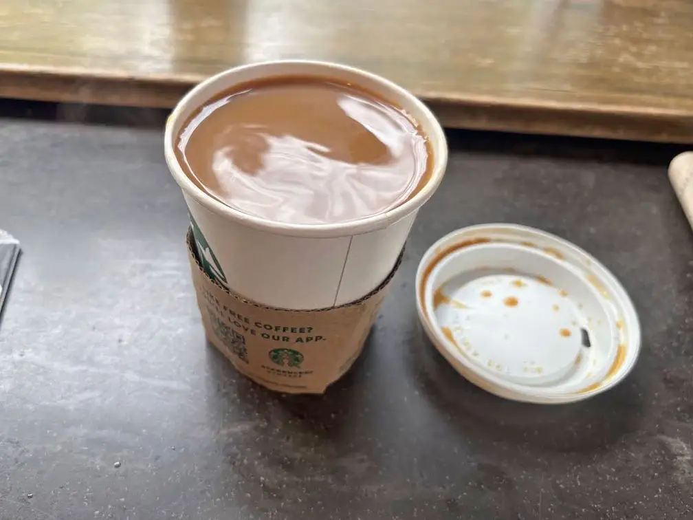A Starbucks blonde-roast coffee with a lid sitting next to it.