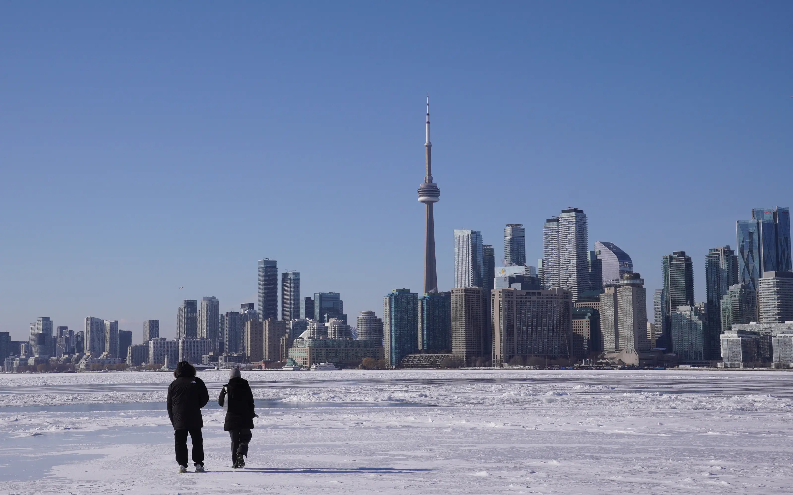 People walk on the frozen surface of Lake Ontario near Ward's Island as below-freezing temperatures continue in Toronto, Ontario, on February 4, 2026.
