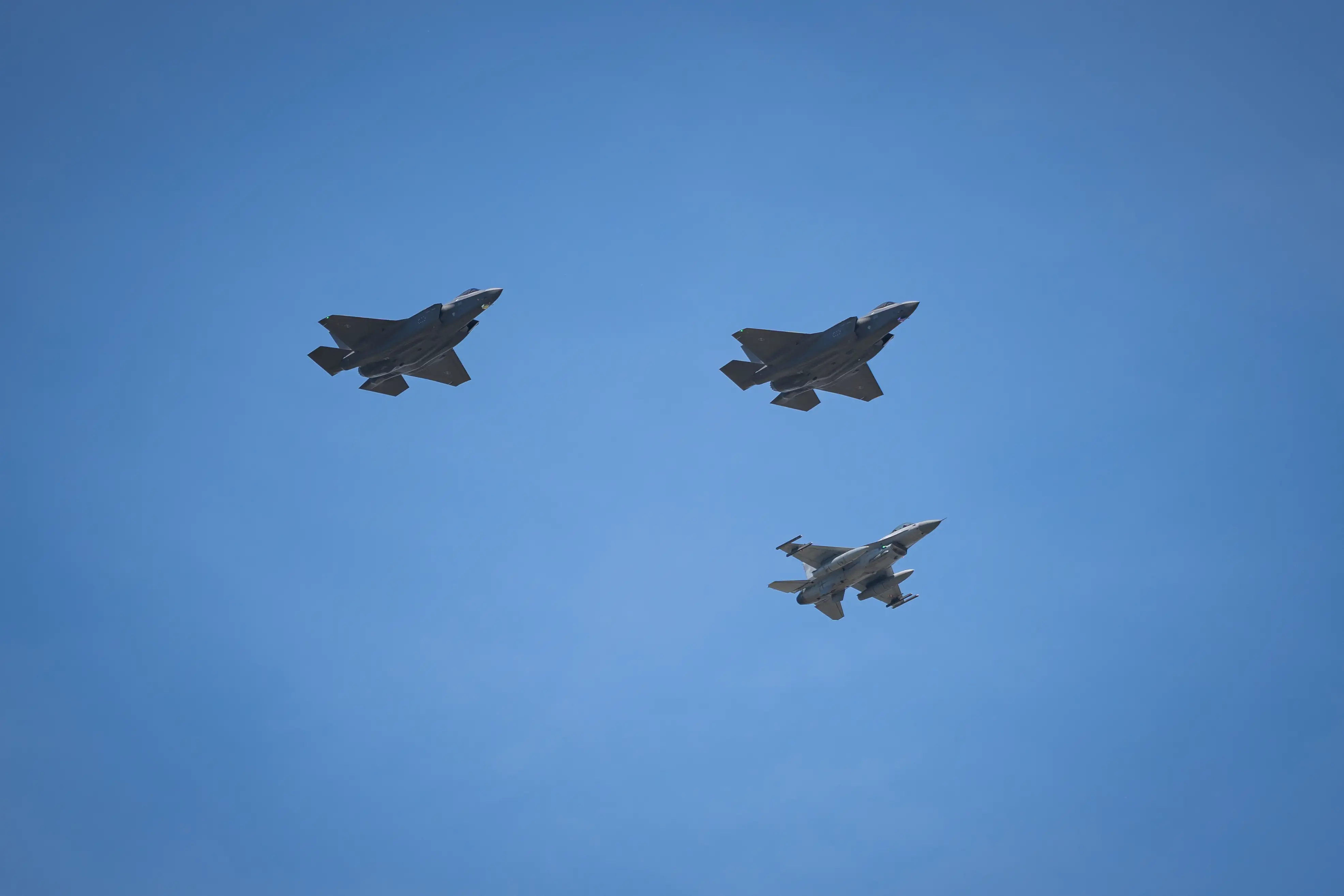 Two Polish Air Force Lockheed Martin F-35A Husarz fifth-generation fighter aircraft, tail numbers 3509 and 3510, fly with a Polish F-16 Jastrzab fighter during the Polish Armed Forces Day military parade in Warsaw, Poland.