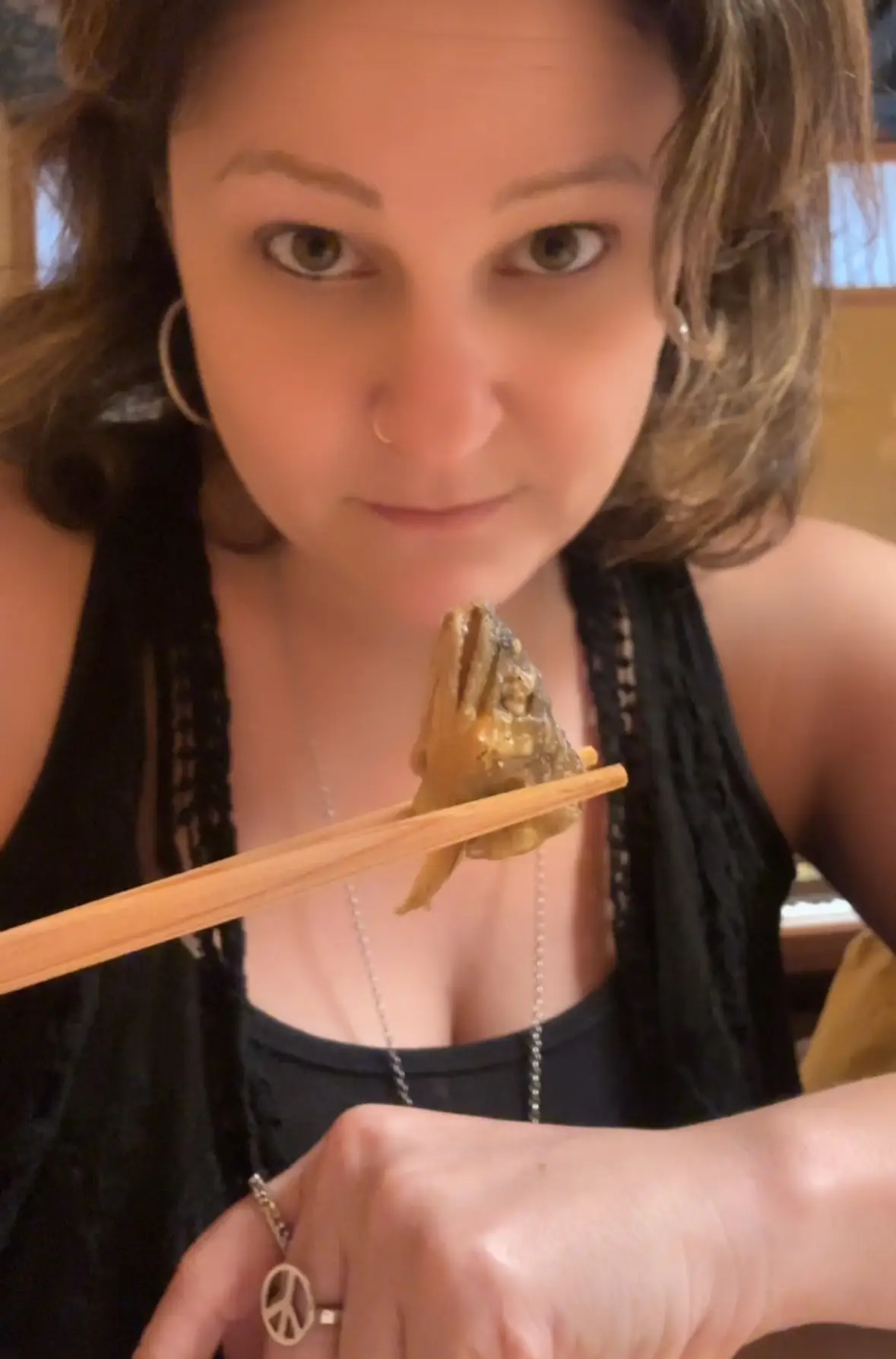 A woman holding ayu sweetfish with chopsticks in Toyama, Japan.
