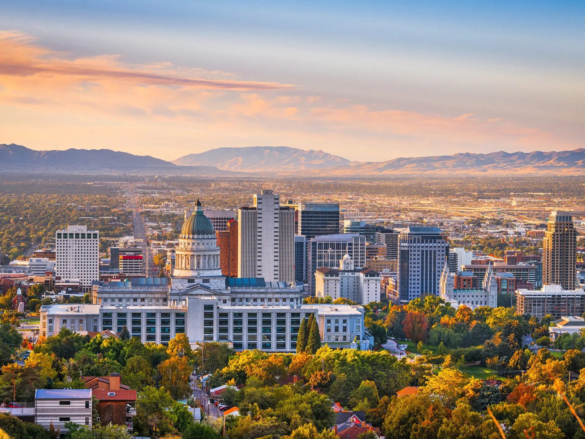 Salt Lake City skyline with the Utah State Capitol dome and mountains at sunset.