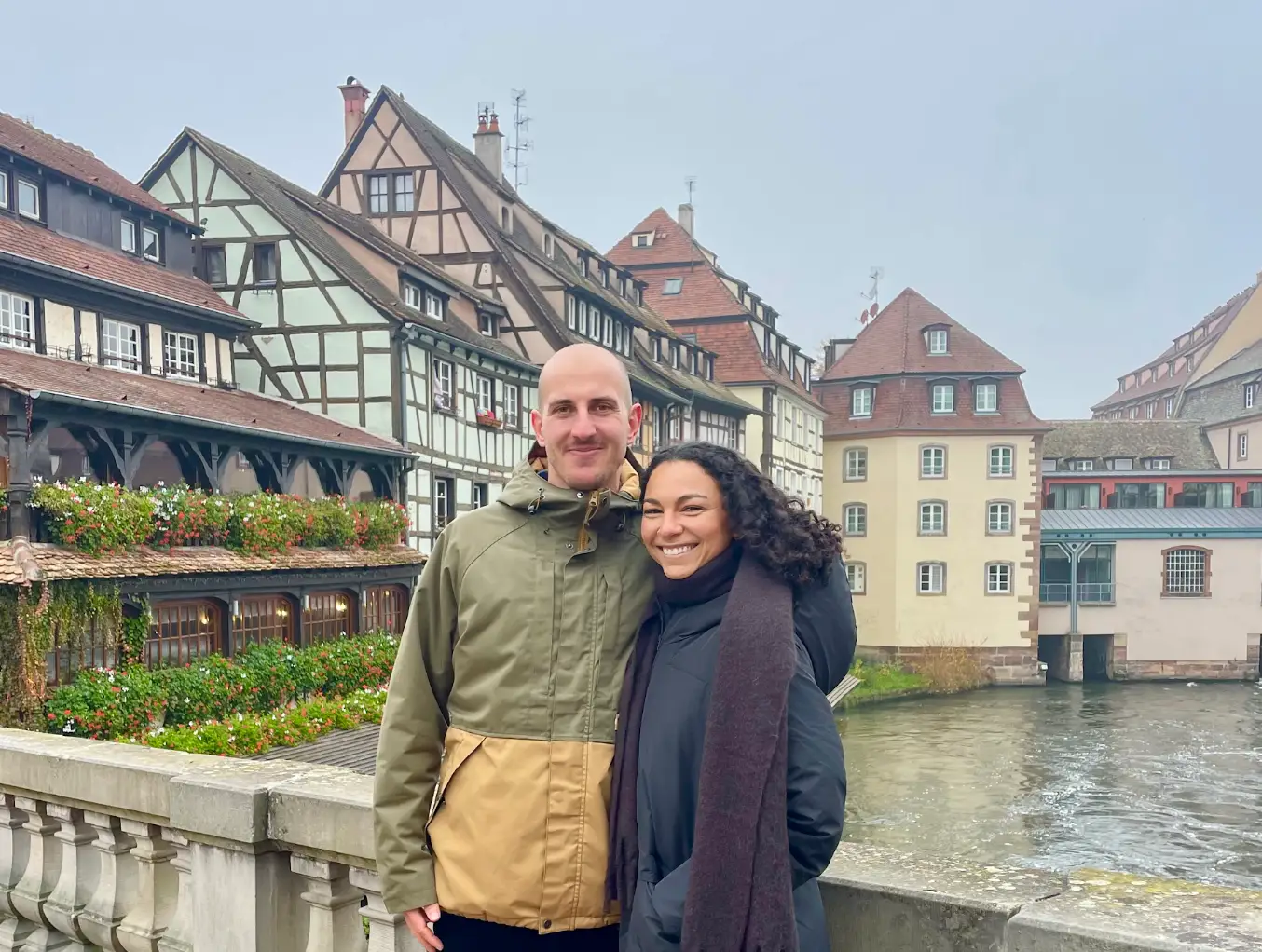 The writer and her partner standing on a bridge in front of old houses in Strasbourg.