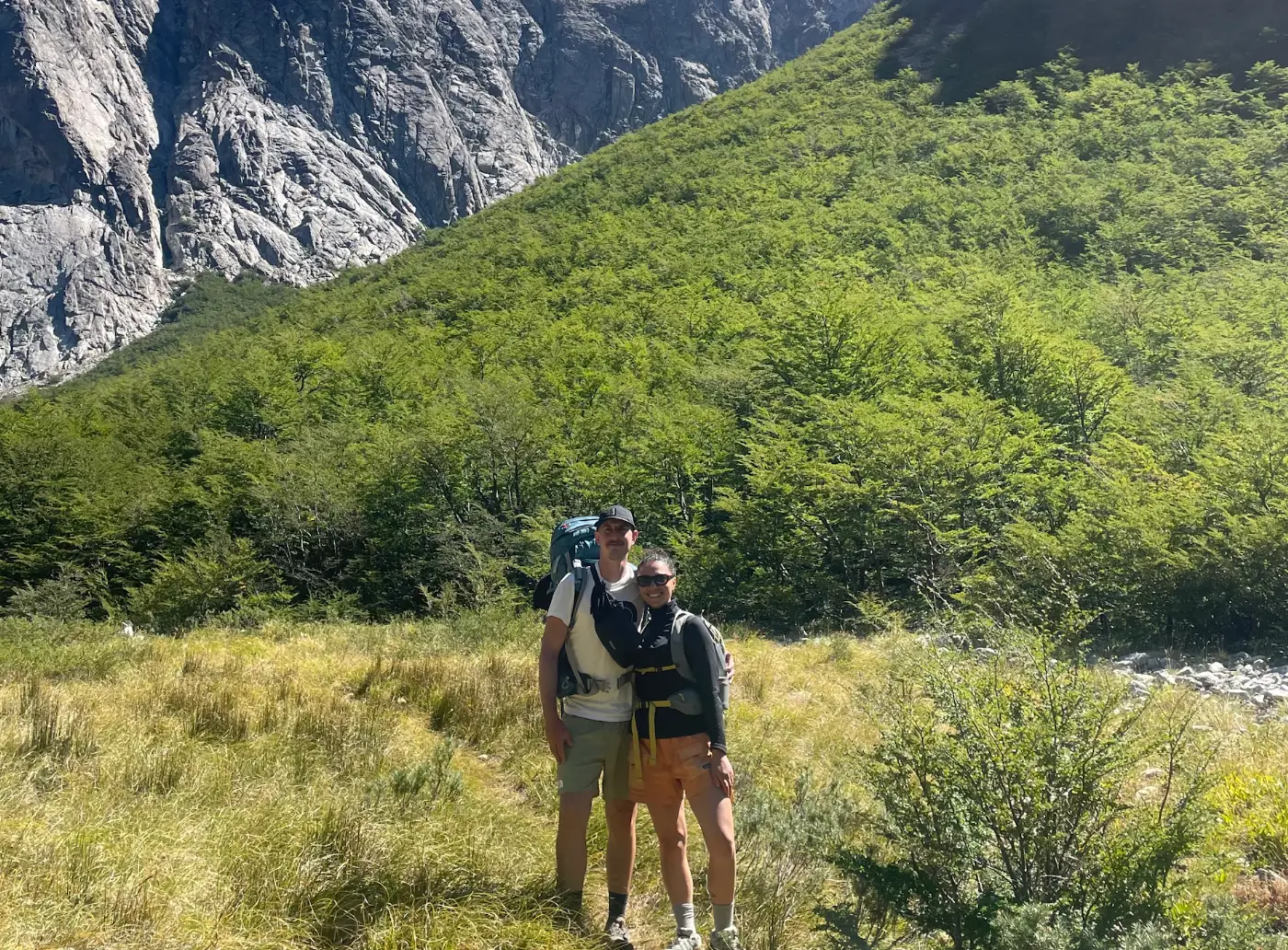 The writer and her partner hiking in Patagonia, standing in front of a hilly mountain.