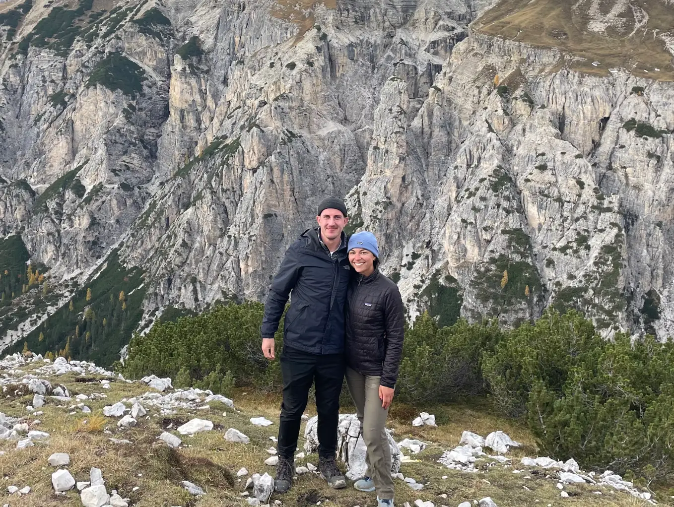 The writer and her partner stand in front of mountains in the Dolomites.