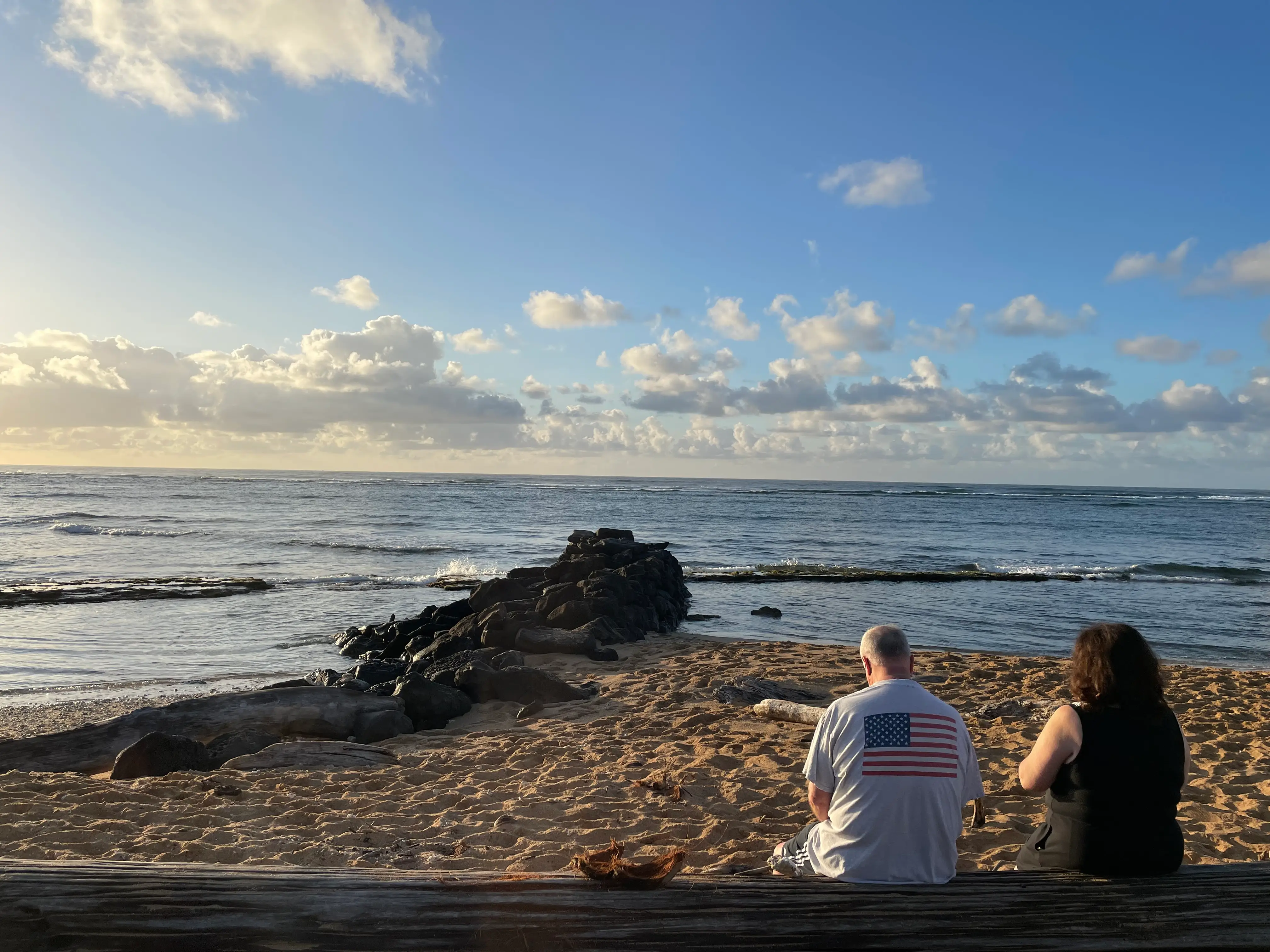 Two people sitting facing water in Hawaii