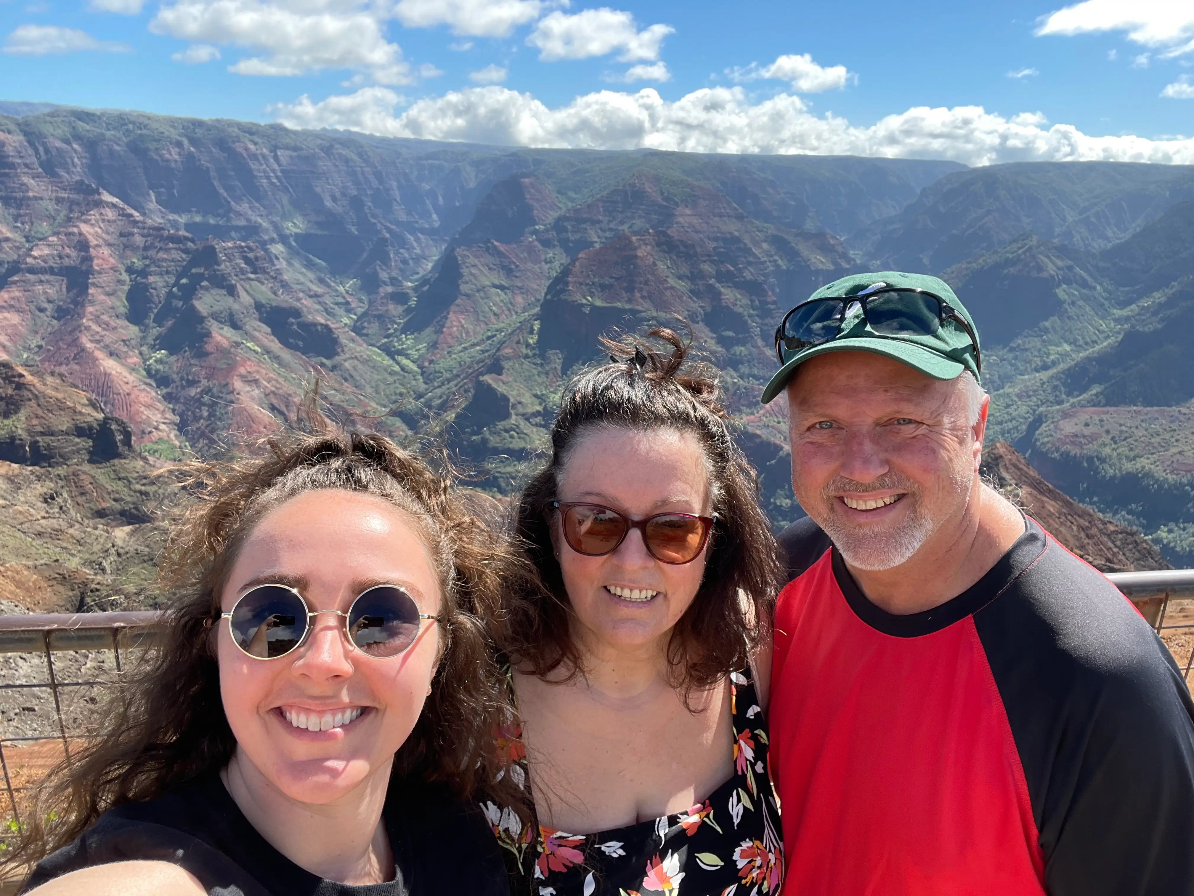Woman and her parents smiling in front of scenic mountain views