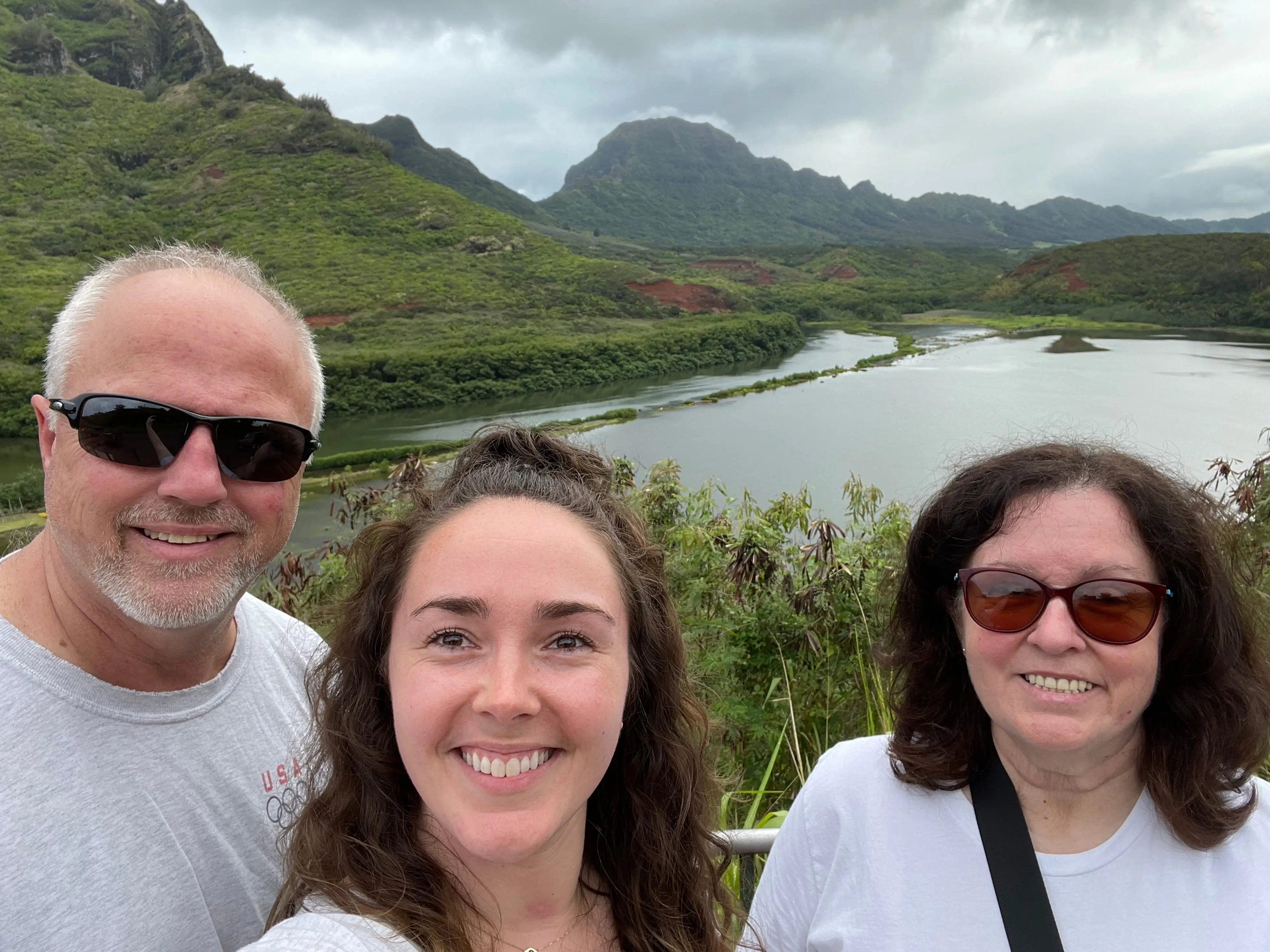 Woman and her parents smiling in front of scenic mountain views