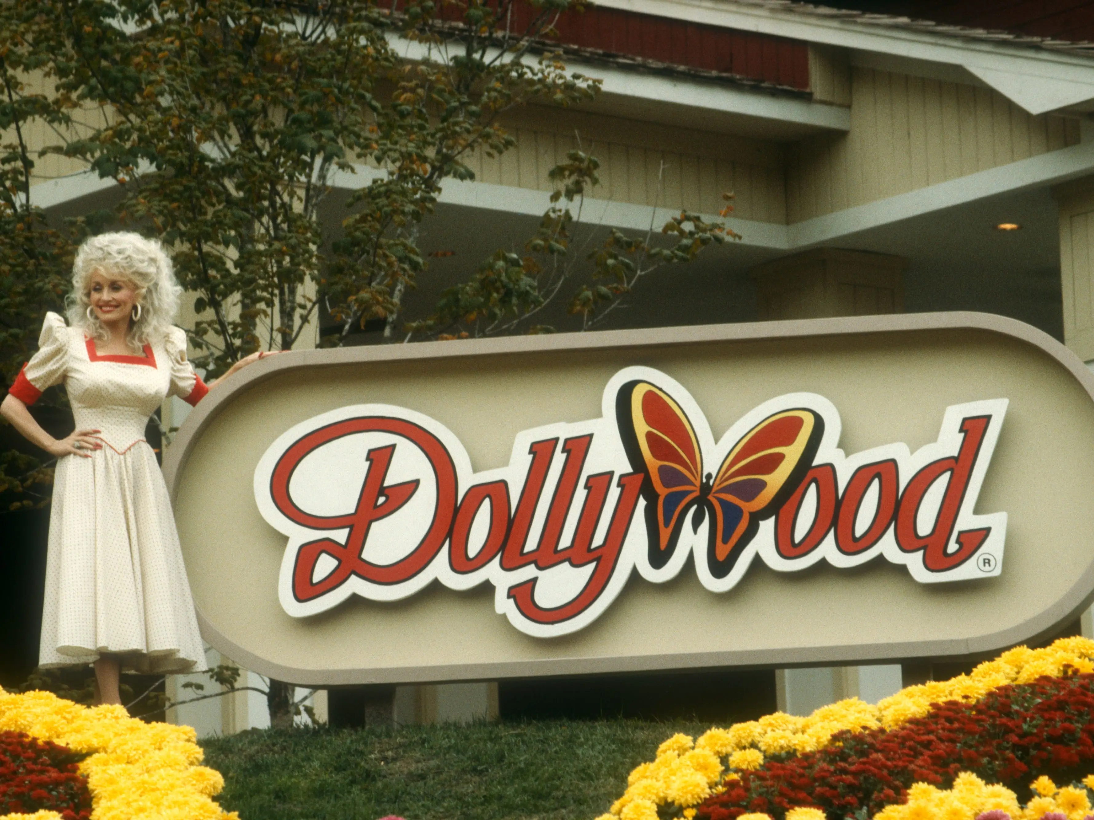 Dolly parton standing in front of the dollywood sign