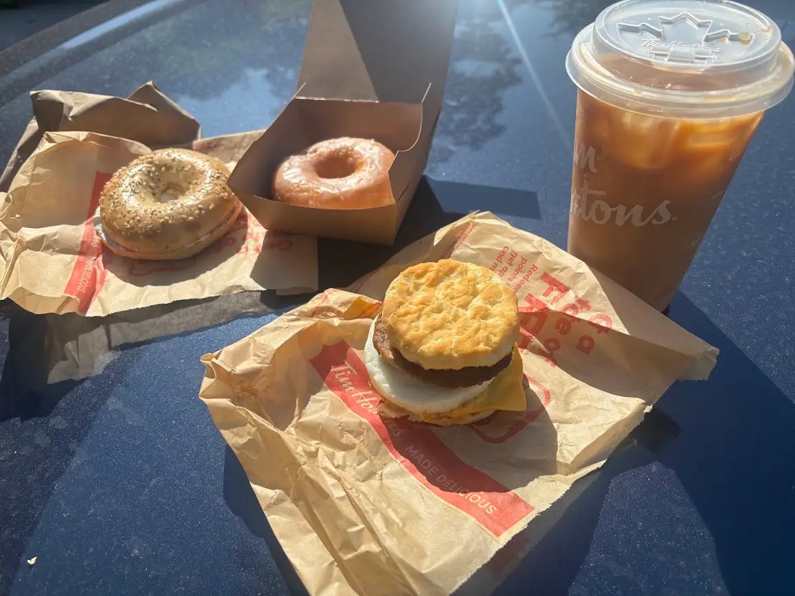 A bagel, doughnut, sausage, egg, and cheese sandwich, and an iced coffee from Tim Hortons.