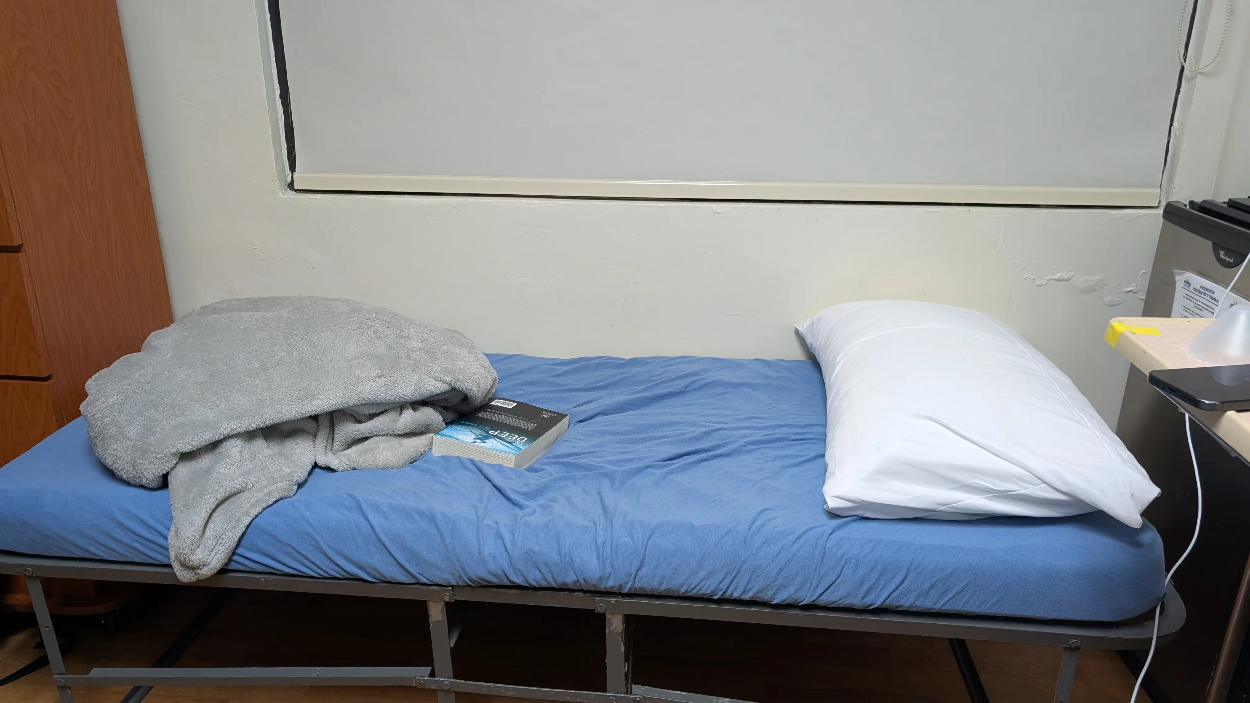 Bed with pillow, blanket, book on it in hopsital room
