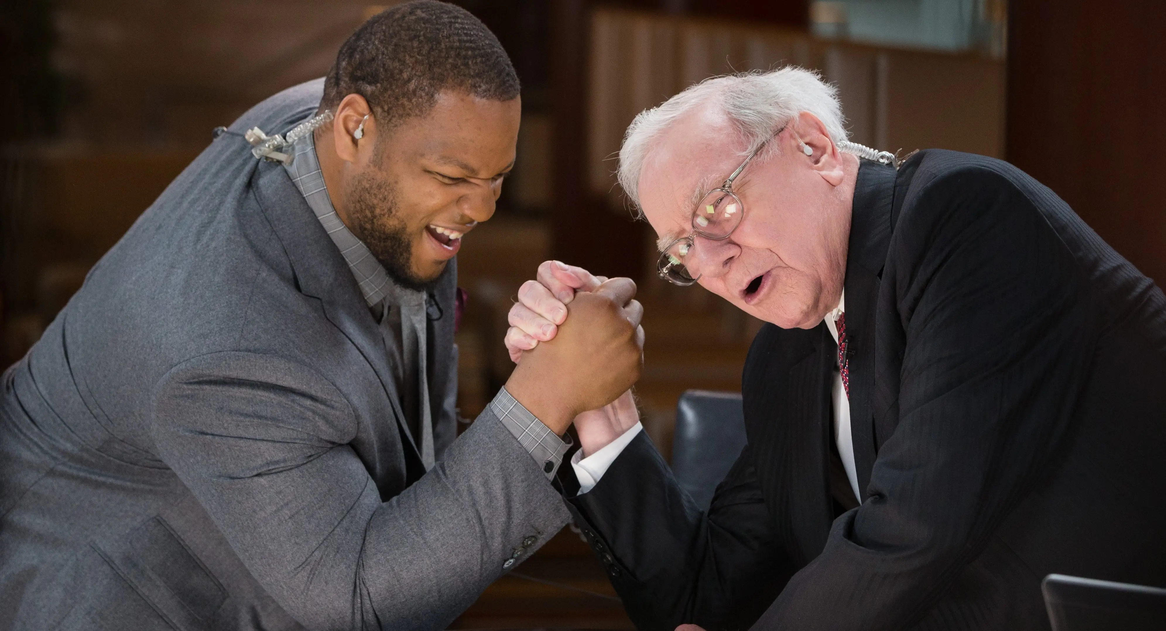 Ndamukong Suh on left arm wrestling Warren Buffett on right.