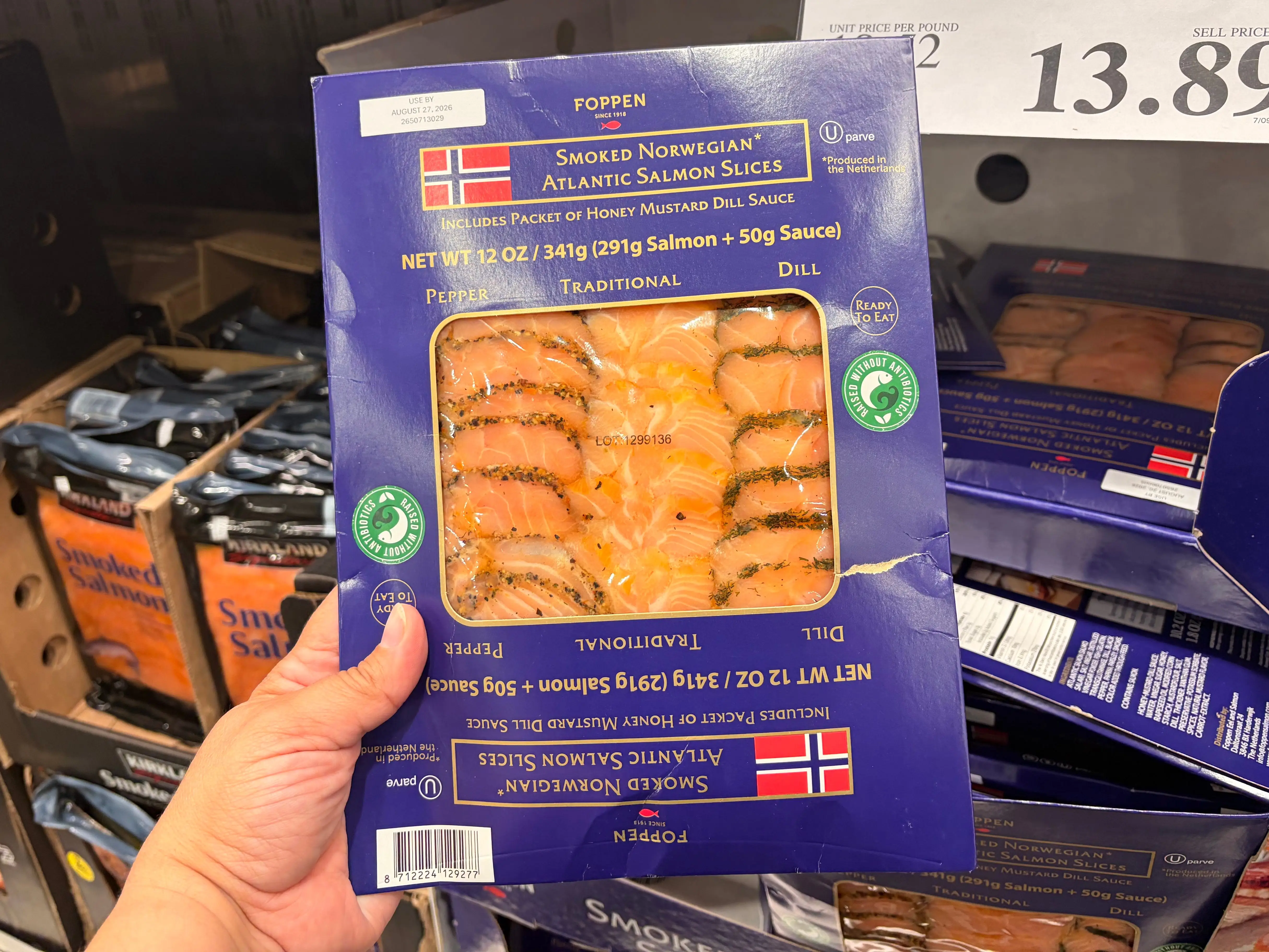 A hand holding a container of Poppen smoked Norwegian Atlantic salmon slices.