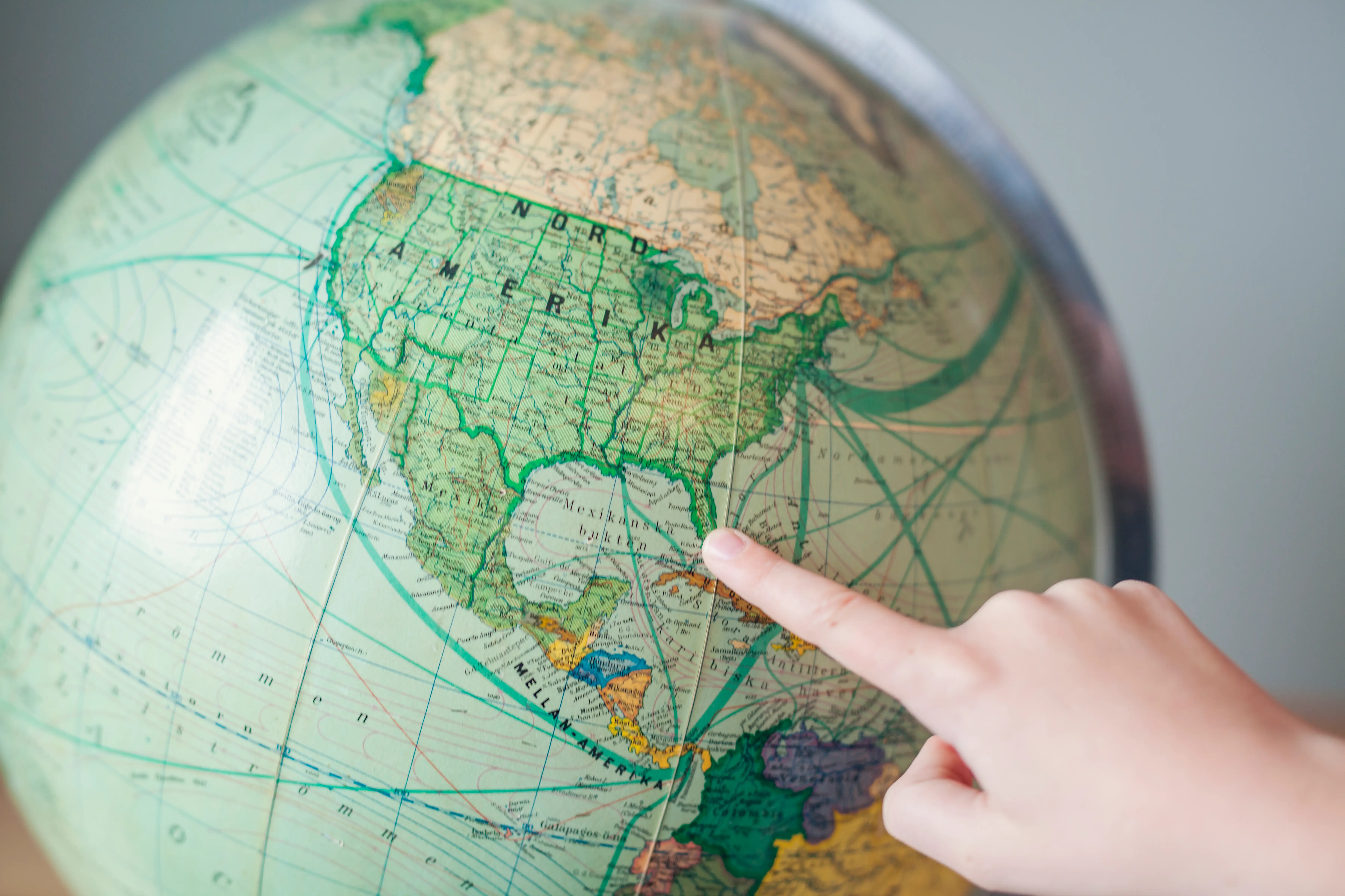 Someone pointing their finger at North America on a globe