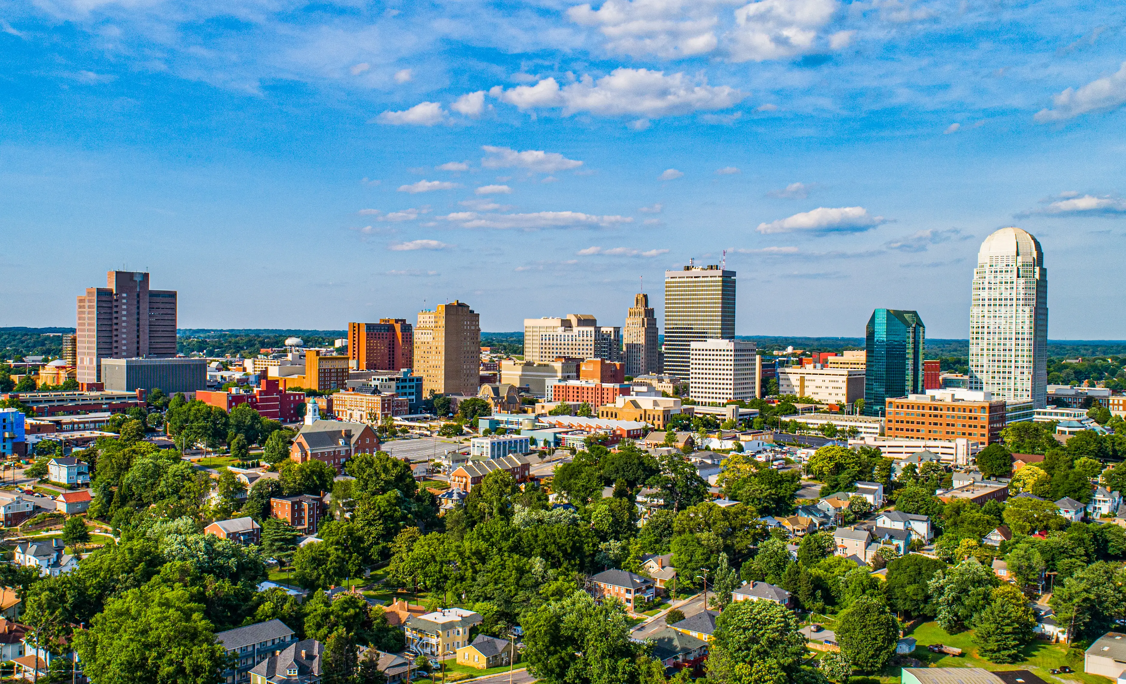 Downtown Winston-Salem skyline rises above tree-filled neighborhoods.