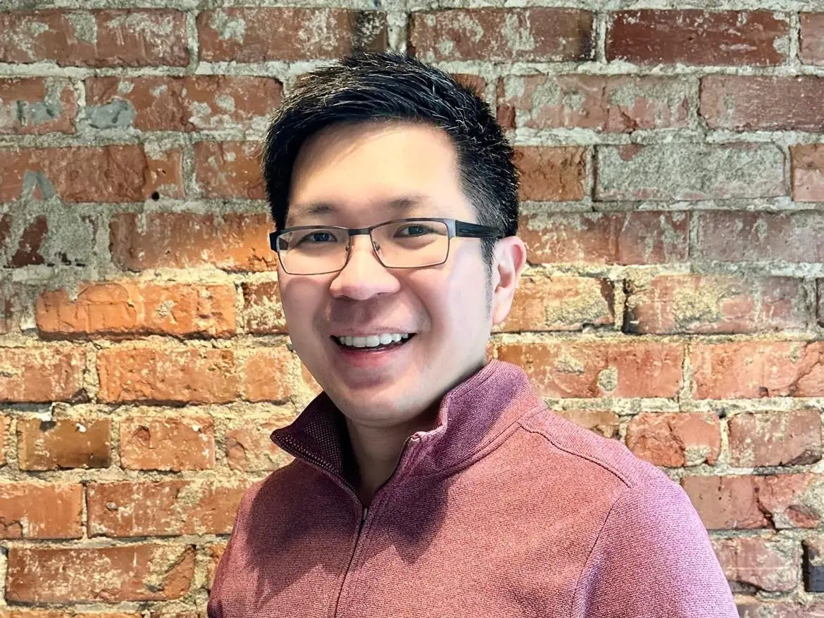 head shot of a man in front of a brick wall