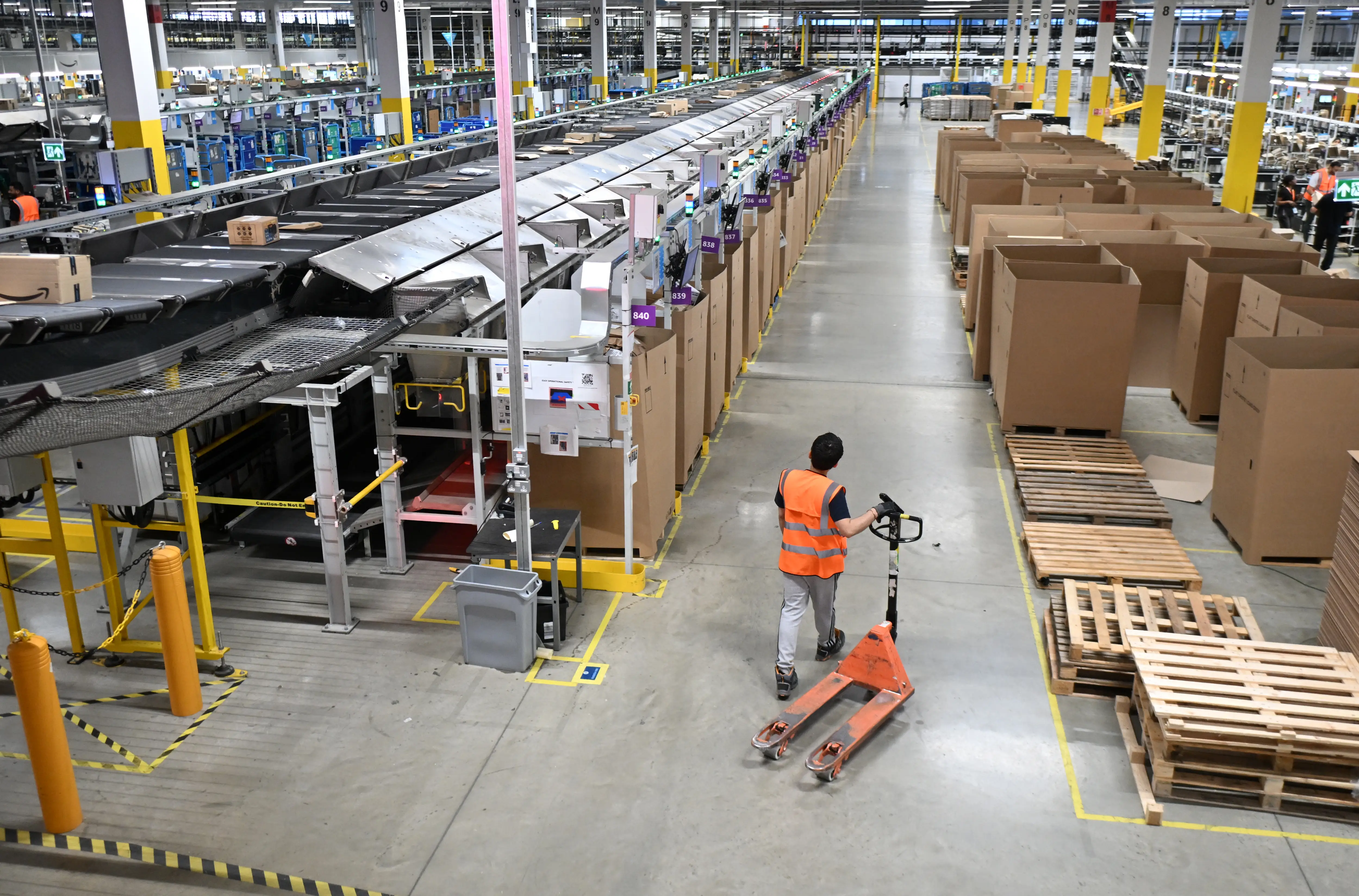 A worker with a hand operated forklift in an Amazon fulfillment center near London