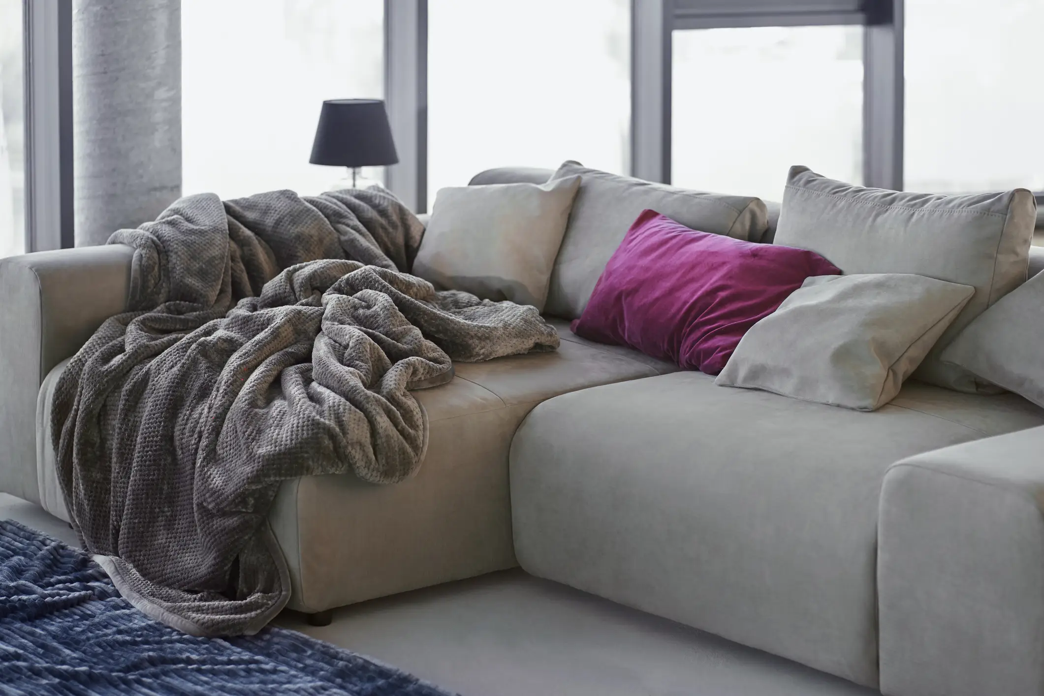 Deep-seated couch with gray blankets, throw pillows