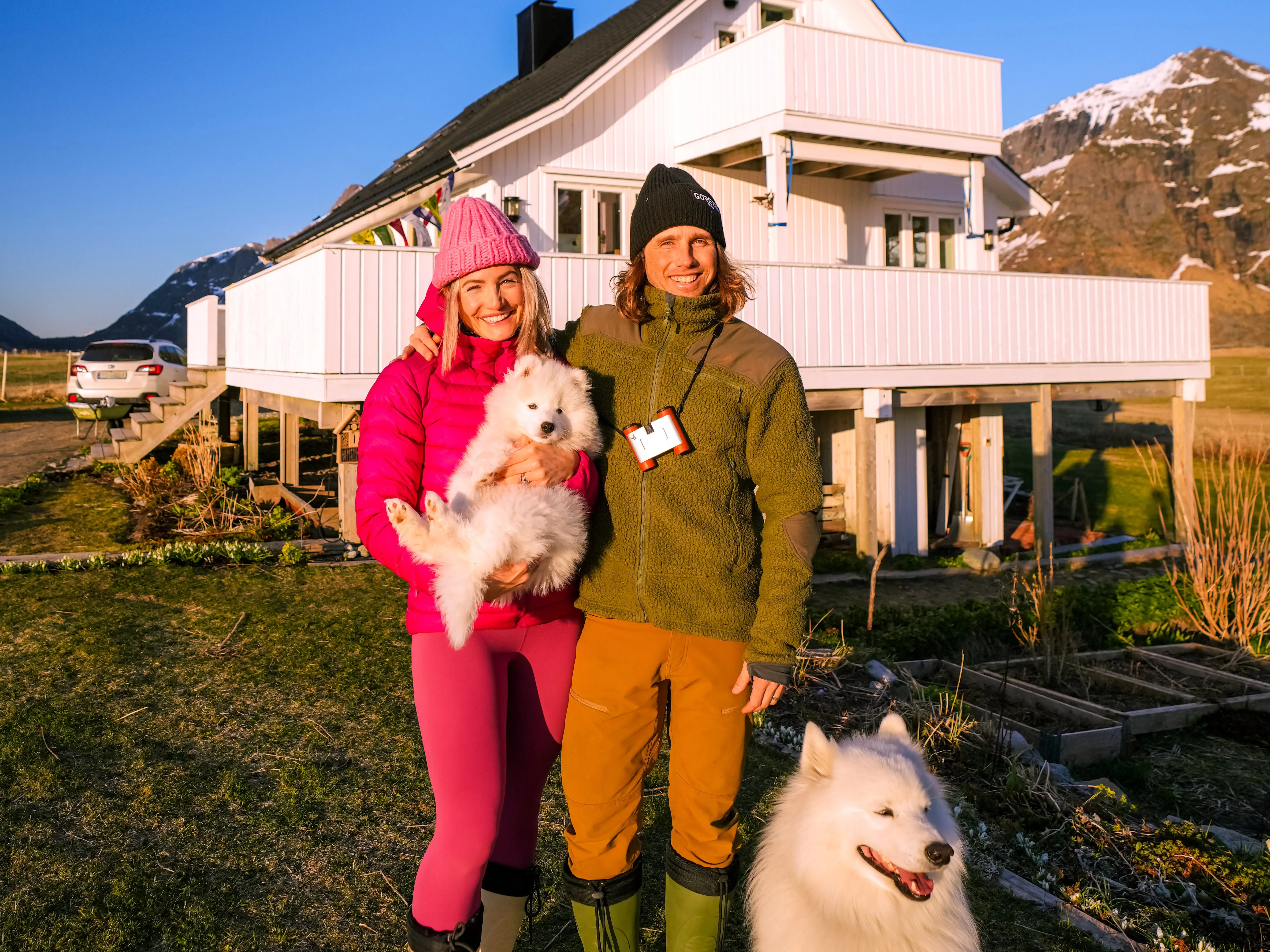 Couple and dog smiling in front of home