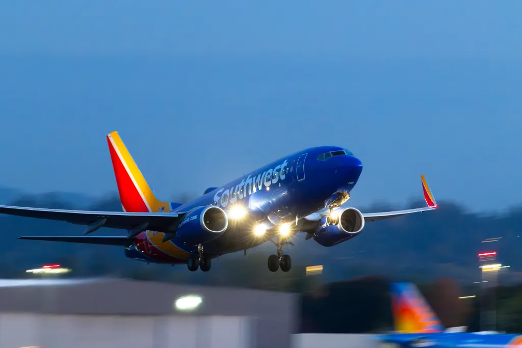 A Southwest Airlines 737 takes off at dusk with its landing lights on.